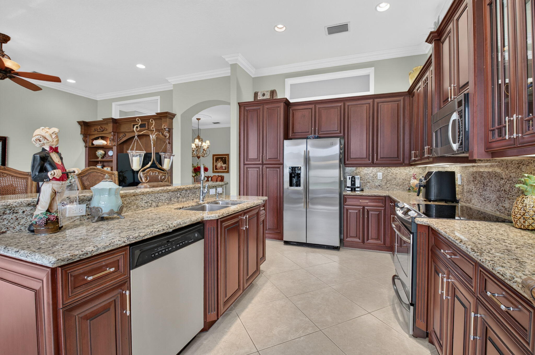 Kitchen featuring raised-panel cherry cabinetry, stone countertops, stainless steel appliances, tile flooring, and recessed lighting