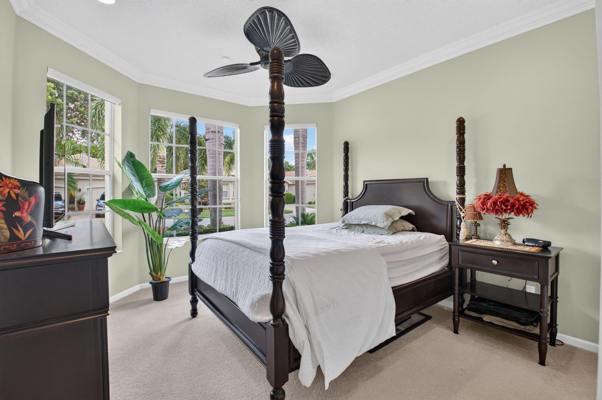 Bay window featuring multi-pane windows, crown molding, neutral carpeting, and a multi-blade ceiling fan