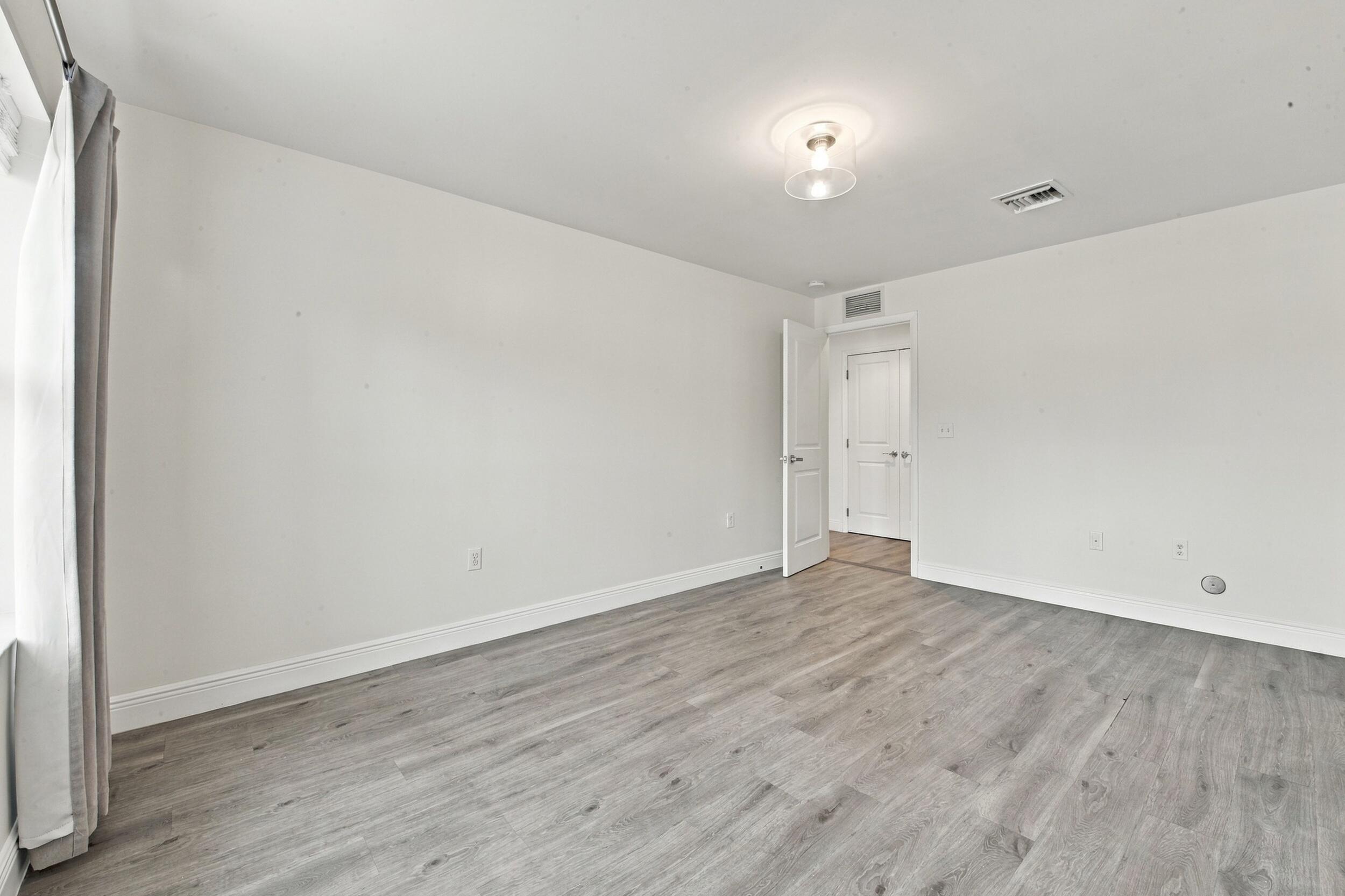Interior space featuring light-toned wood-finish flooring, neutral walls, a flush-mount circular light fixture, and a white interior door