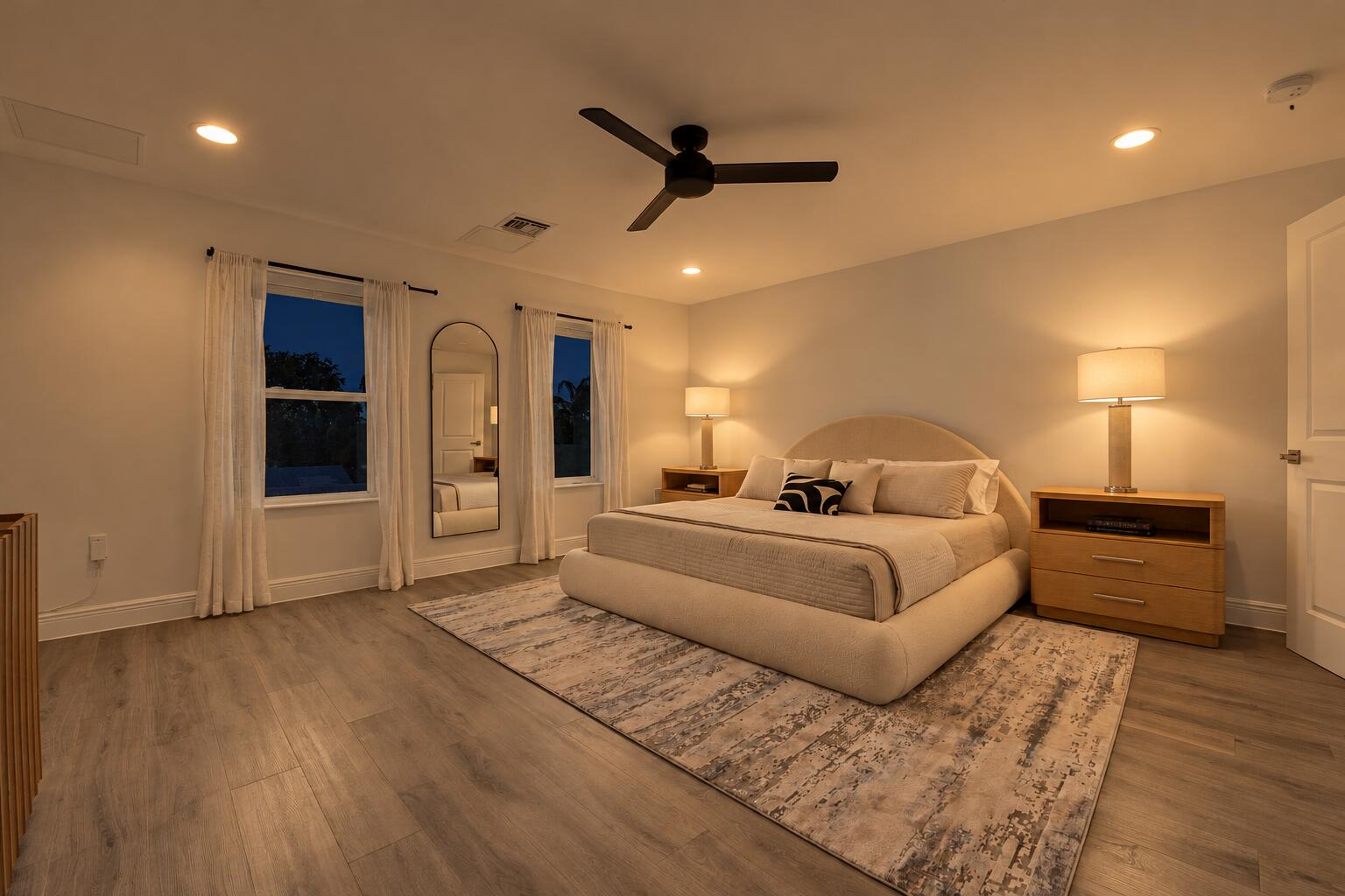 Spacious room featuring light wood-finish flooring, recessed lighting, and a matte black ceiling fan