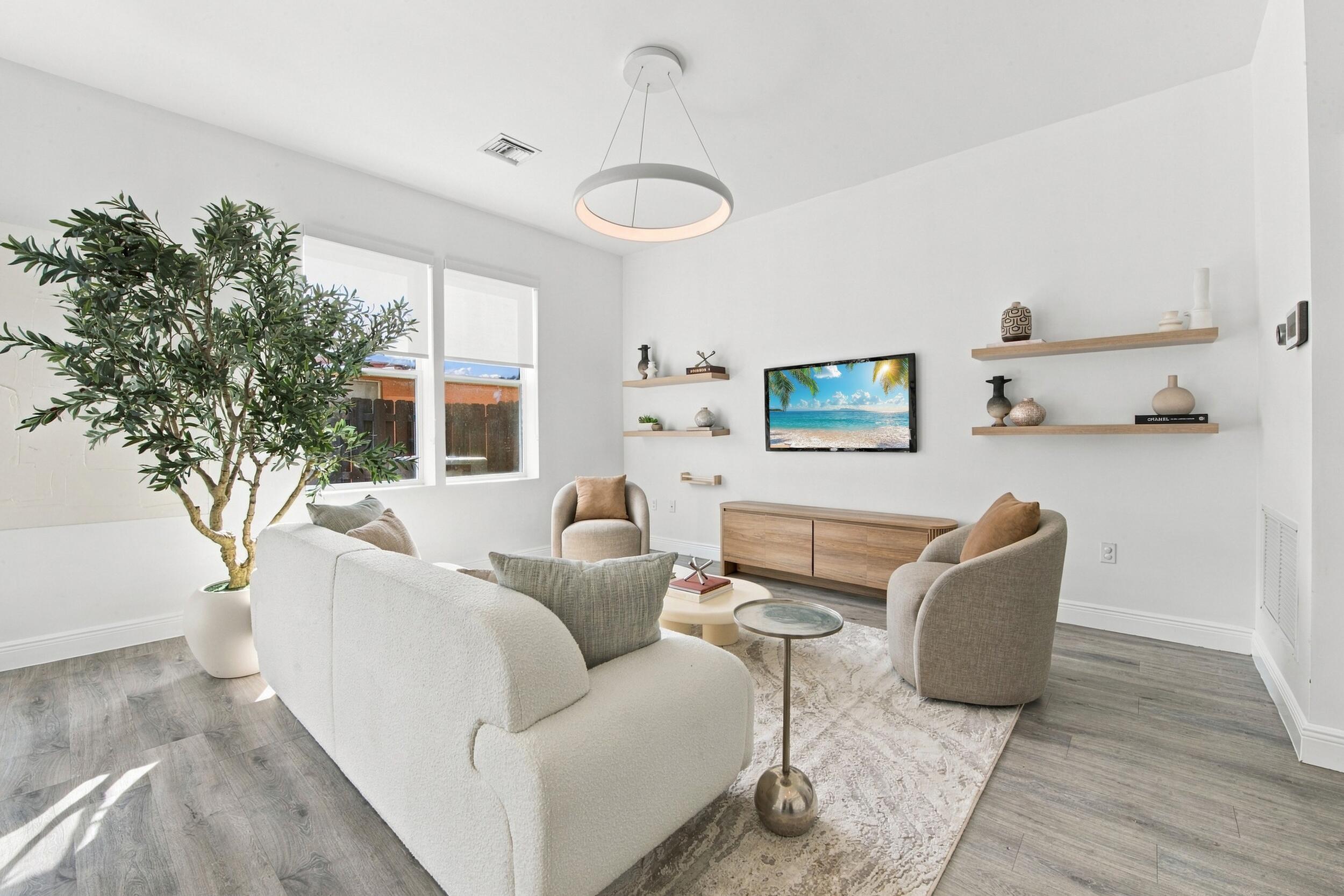 Living space featuring wood-finish flooring, recessed lighting, double-pane windows, and minimalist wall-mounted shelving Living space featuring wood-finish flooring, recessed lighting, double-pane windows, and minimalist wall-mounted shelving