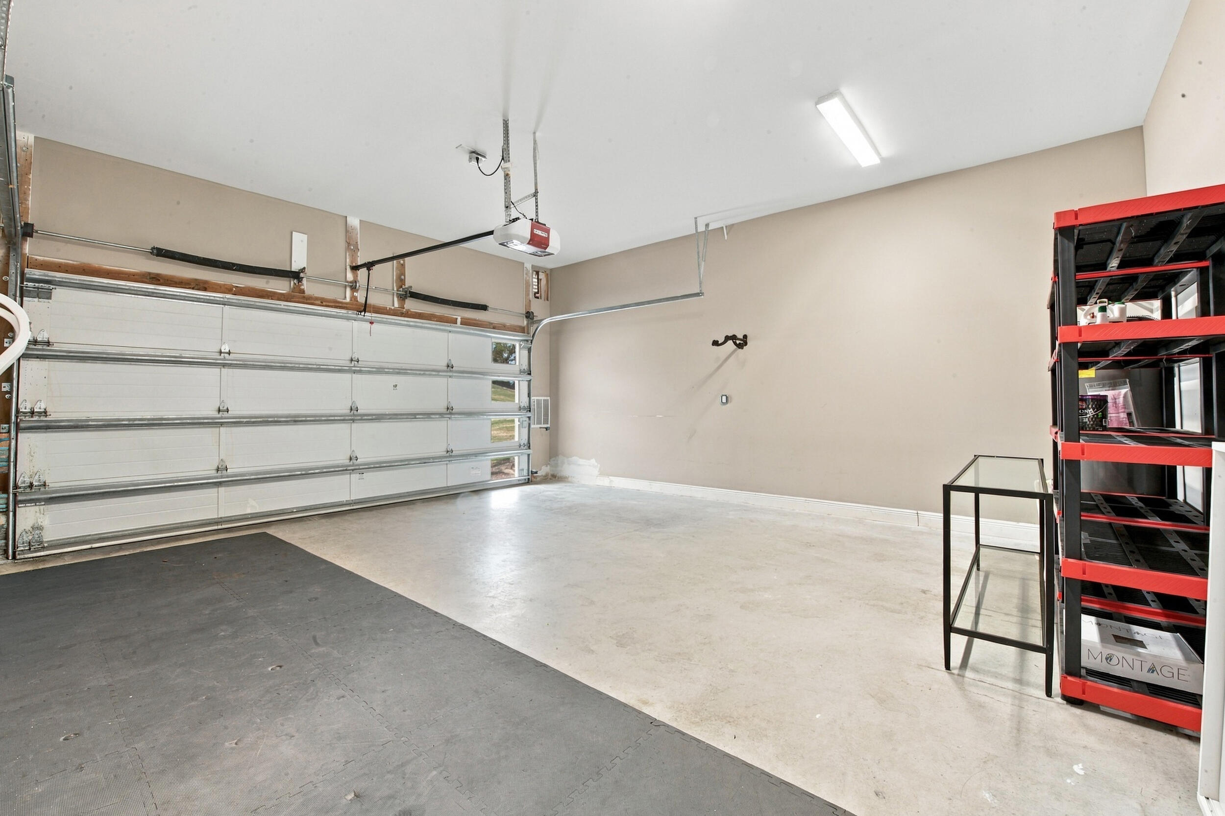 Attached two-car garage featuring a sectional overhead door, concrete flooring, and linear overhead lighting