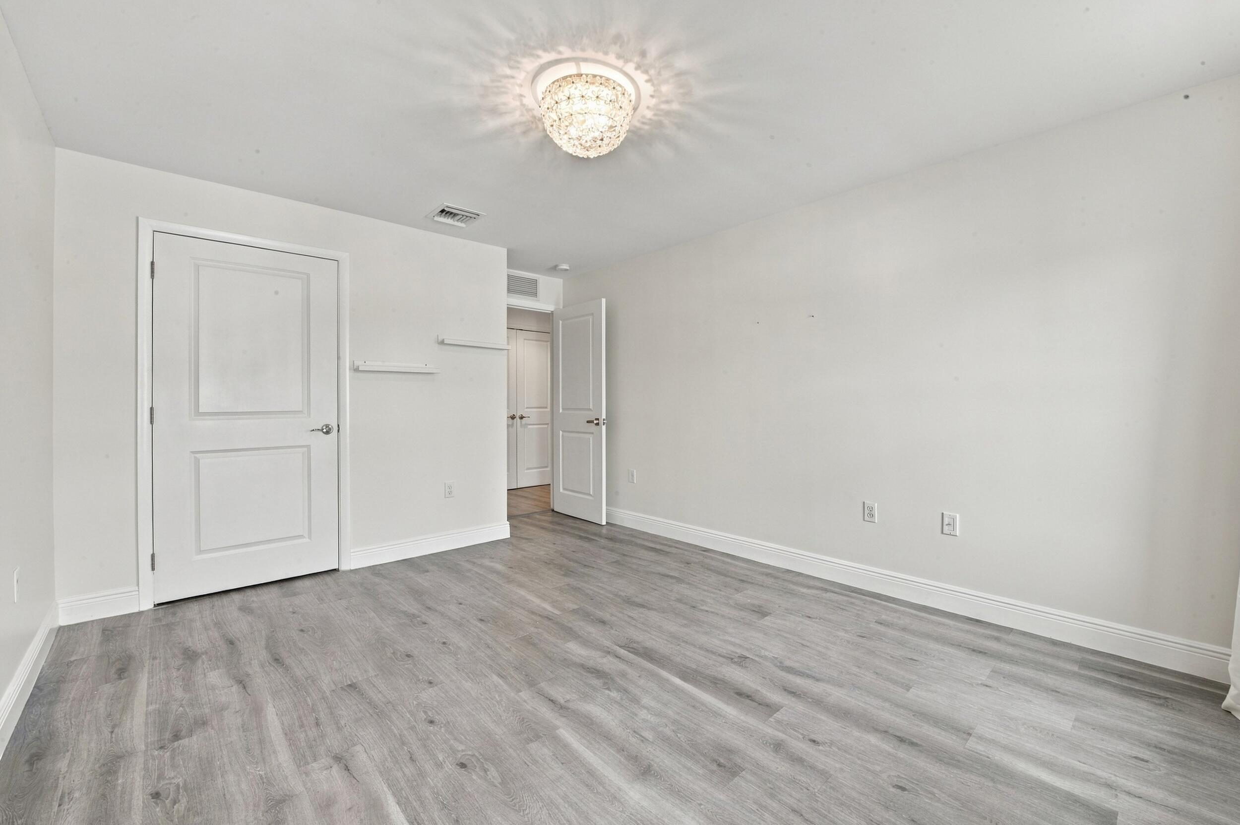 Room interior featuring wood-finish flooring, a multi-tiered crystal flush-mount light fixture, and two panel doors