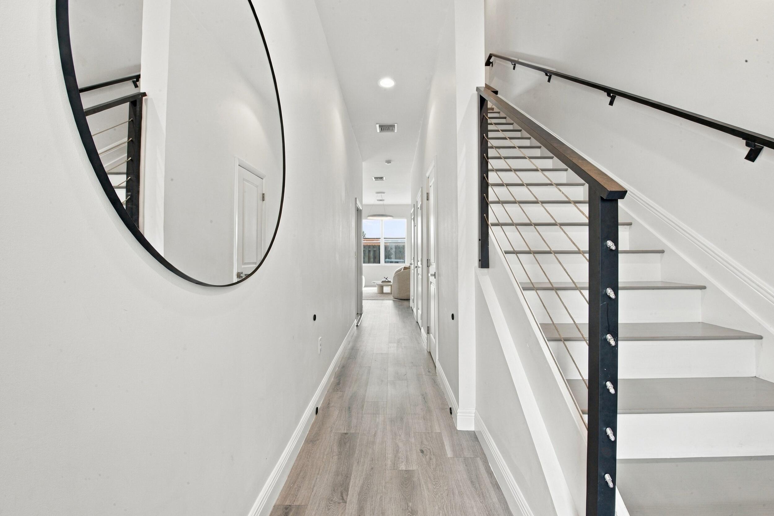 Hallway featuring wood-finish flooring, recessed lighting, and a staircase with a matte black metal railing and horizontal cable balusters