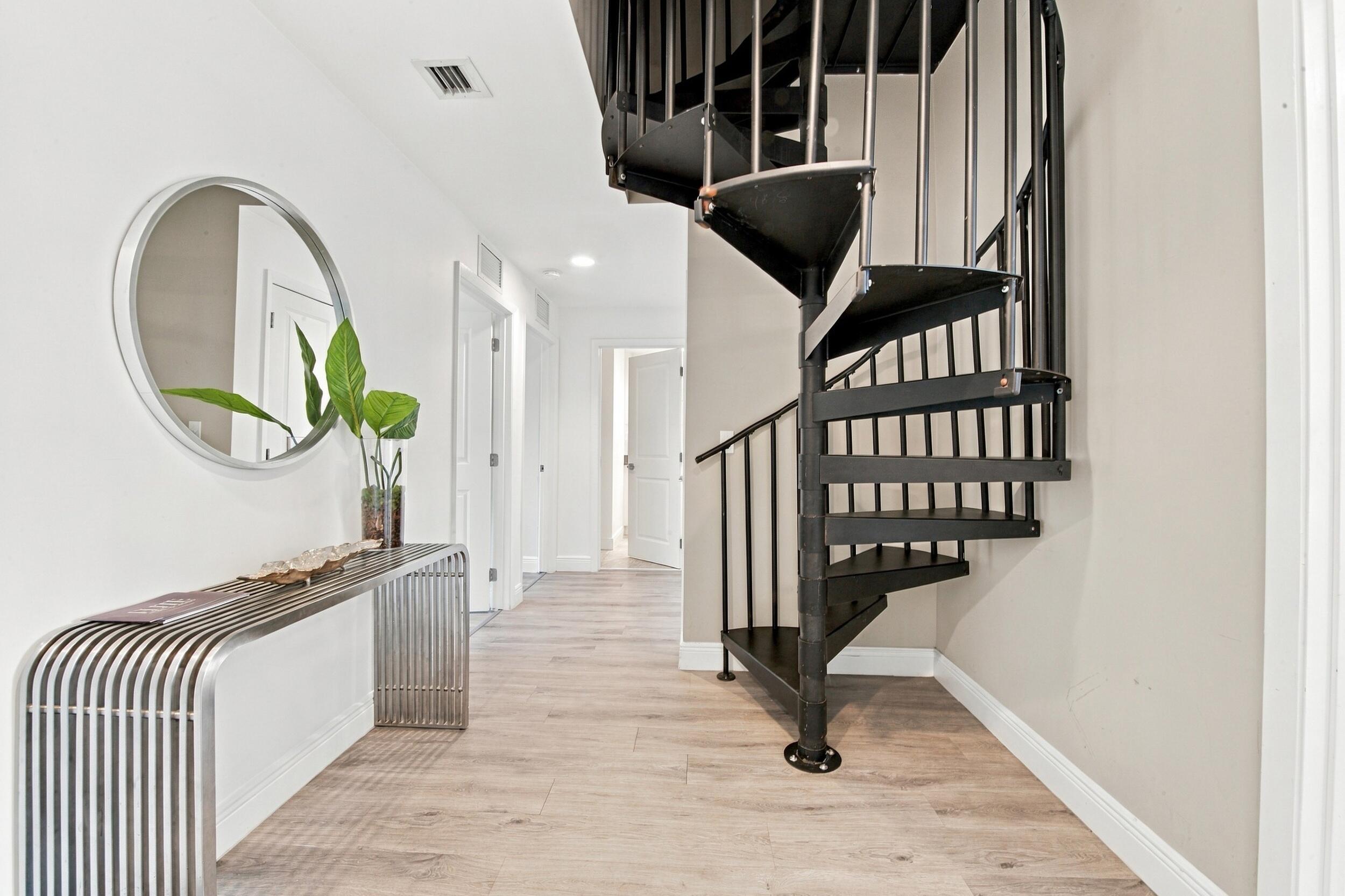 Black metal spiral staircase featuring open risers and vertical balusters, complemented by wood-finish flooring