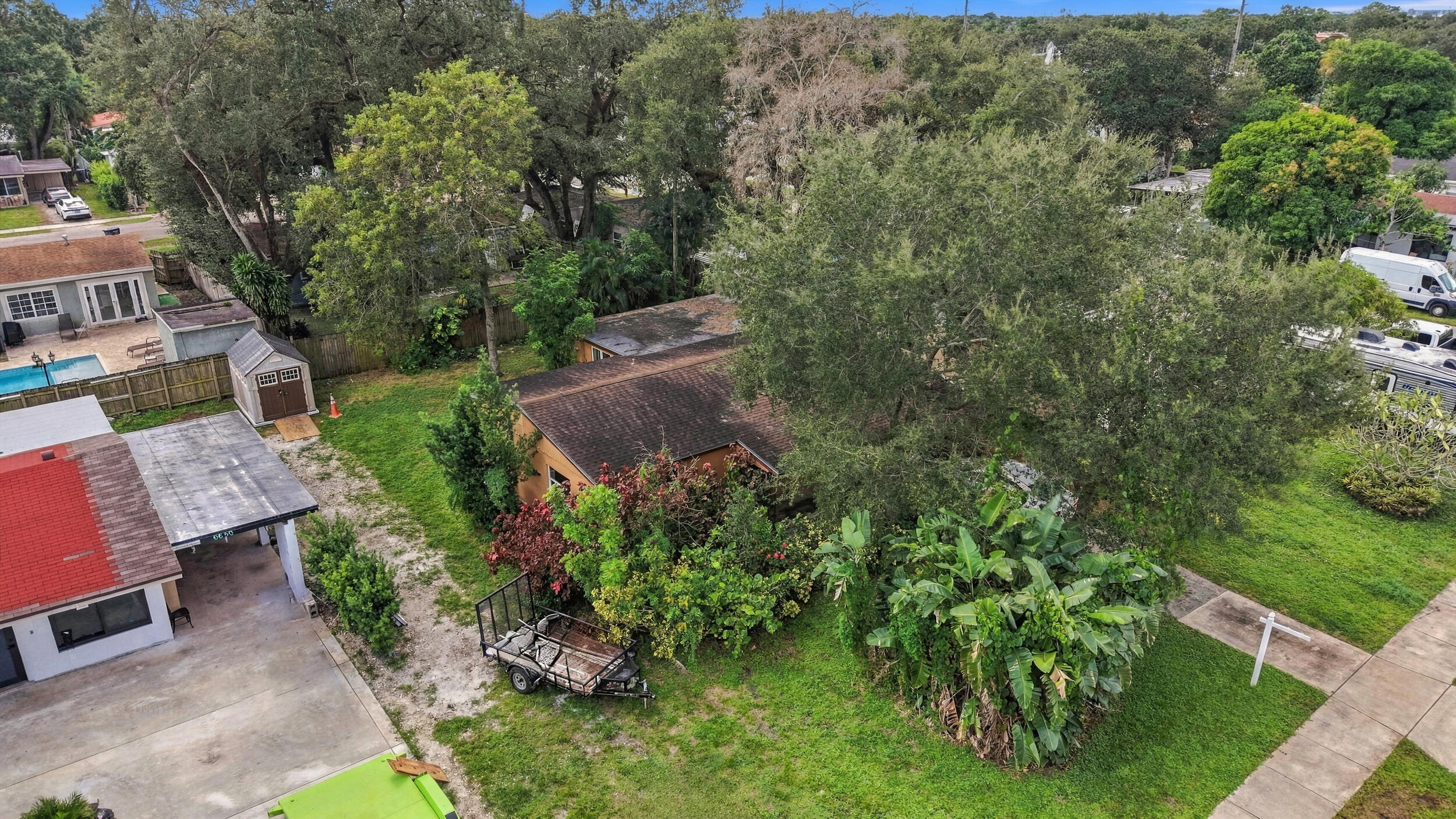 Expansive lot featuring mature shade trees, established landscaping, and a detached storage shed