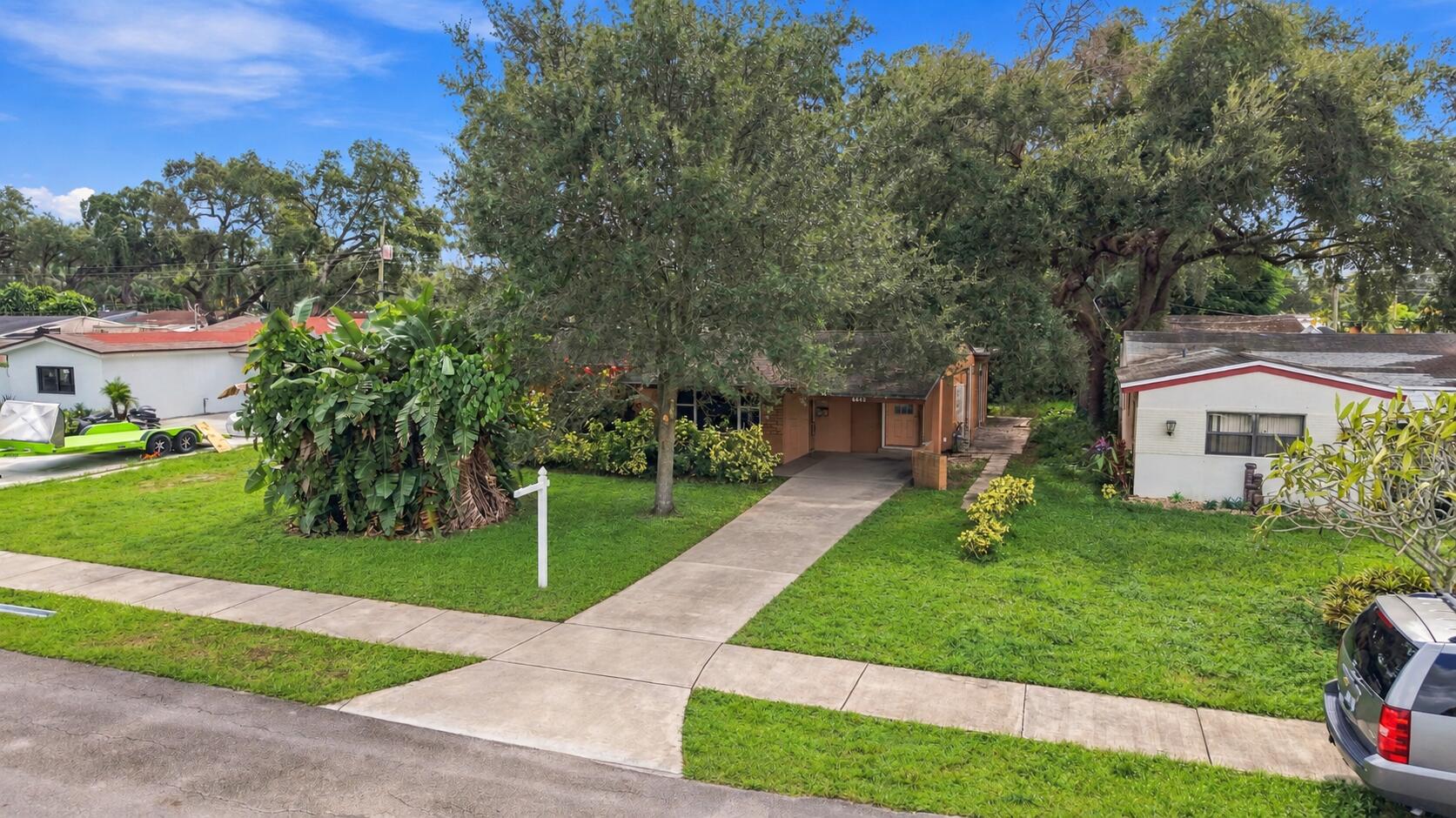 Exterior featuring a concrete walkway, mature trees, and landscaping