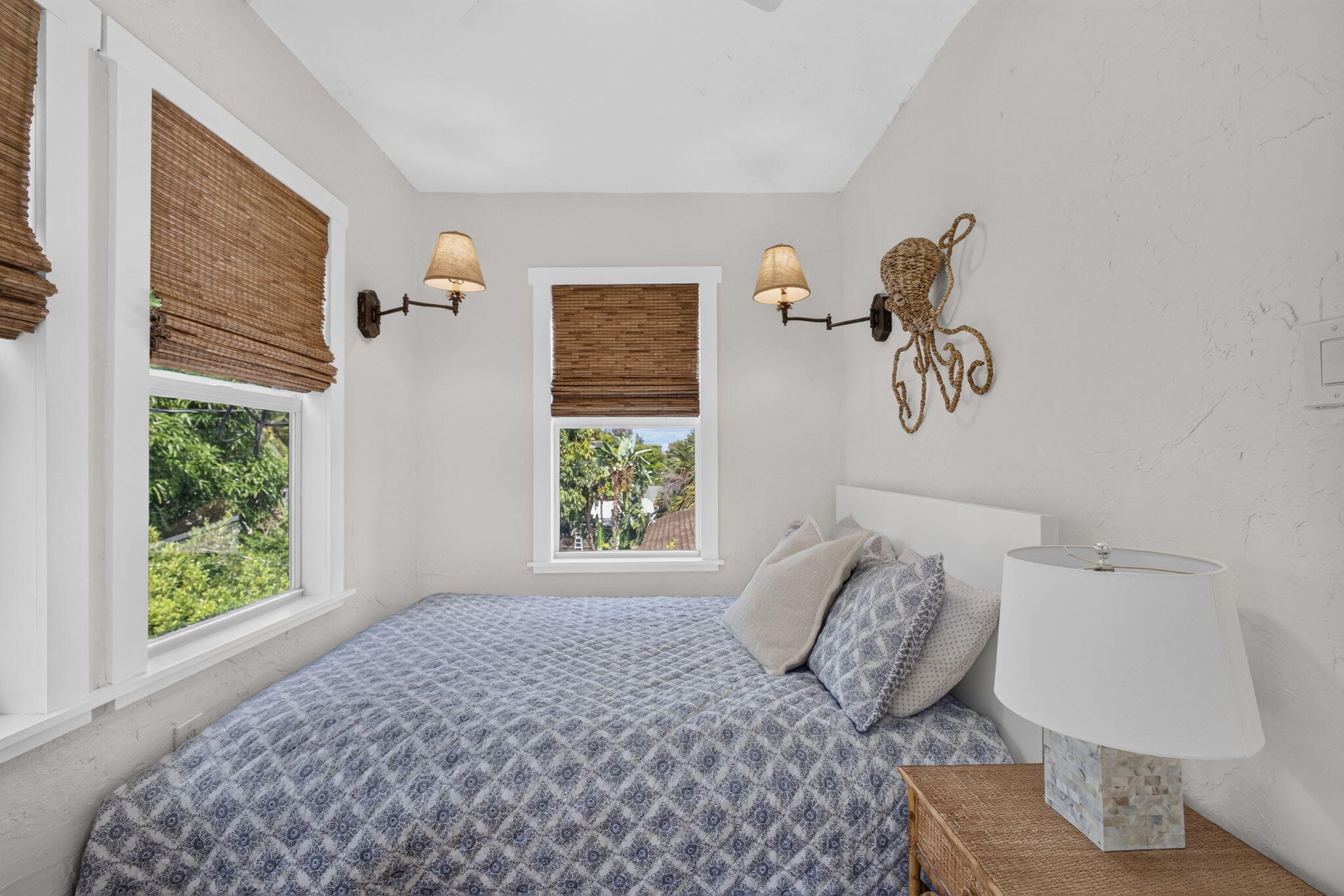 Multi-window room featuring textured white walls, twin adjustable wall-mounted sconces, and natural woven shades