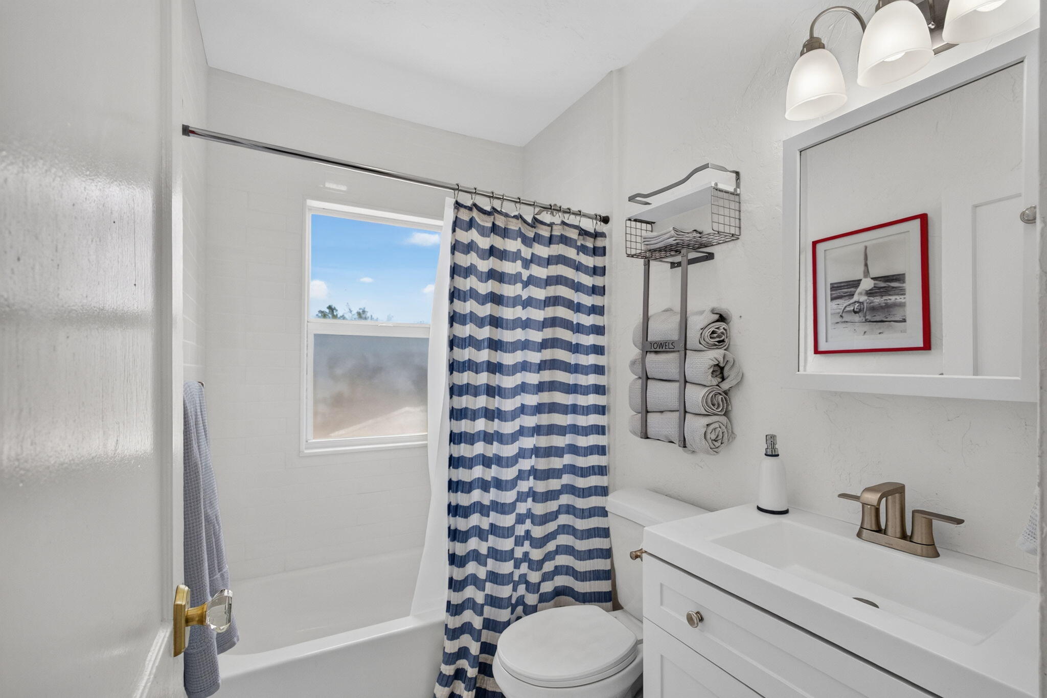 Bathroom featuring a white vanity with an integrated sink, brushed-metal faucet, wall-mounted medicine cabinet, triple-light vanity fixture, and a tub-shower combination