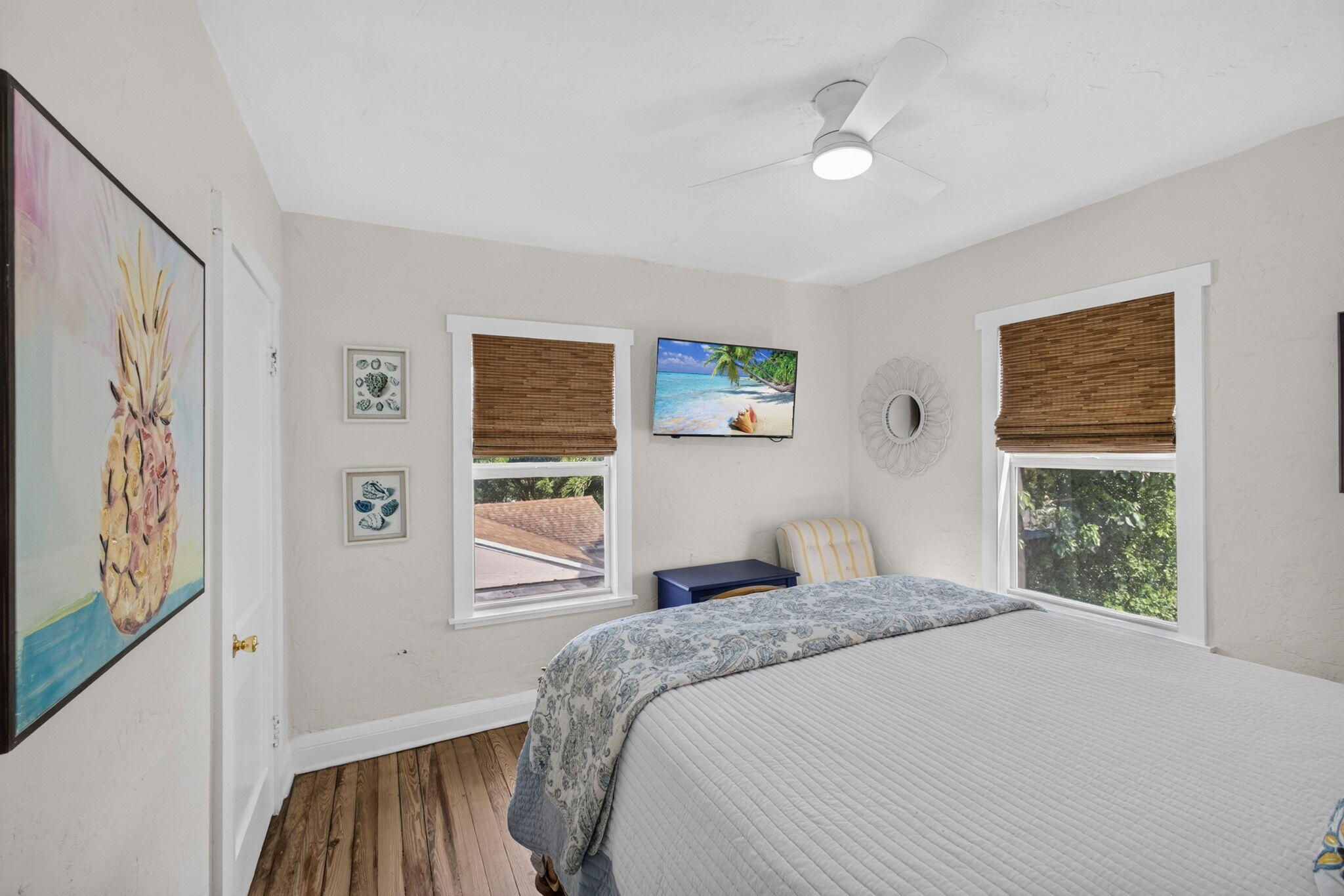 Interior space featuring wood-finish flooring, two windows with white trim, and a modern ceiling fan with integrated lighting