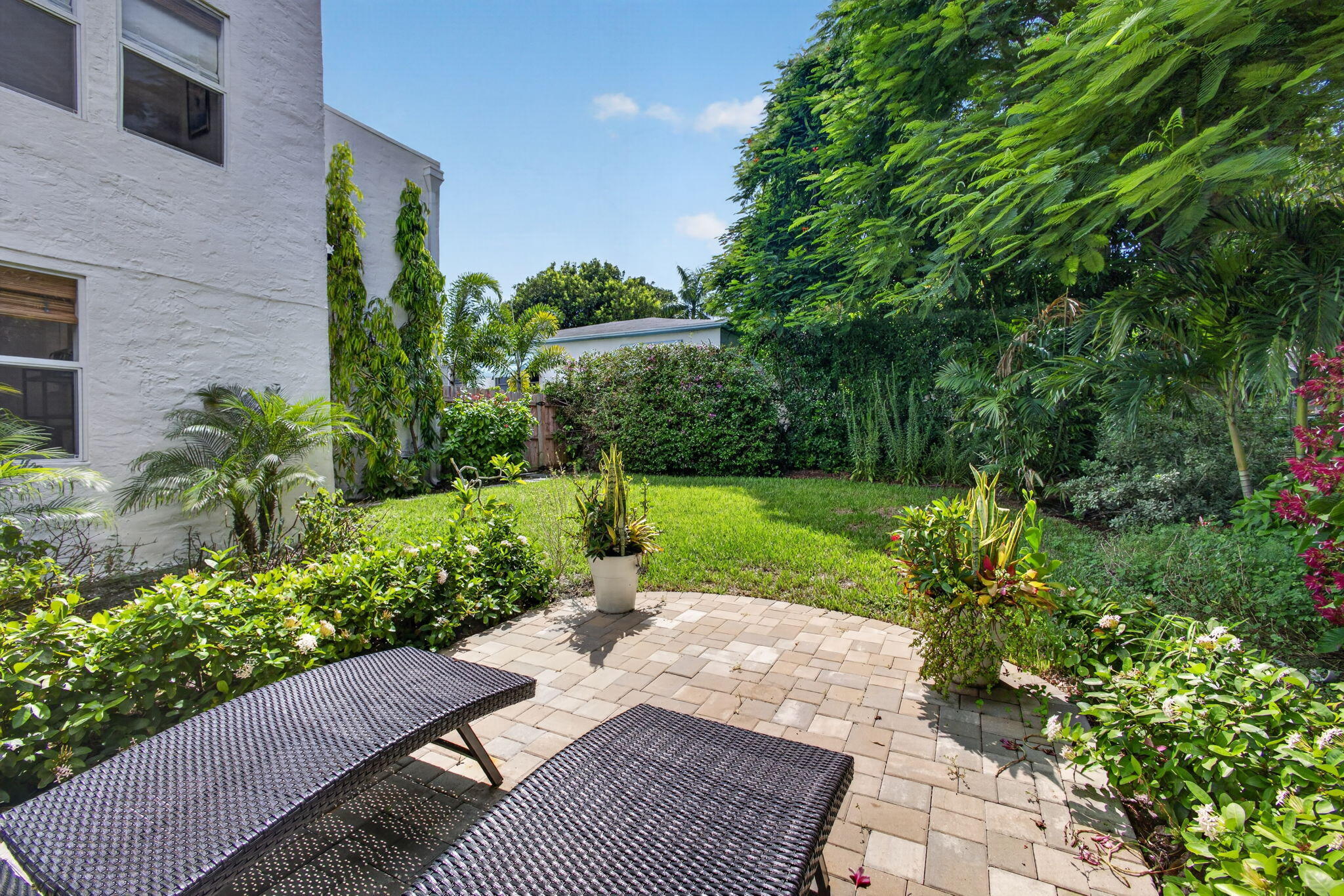 Backyard featuring a paved stone patio, manicured lawn, and established perimeter landscaping