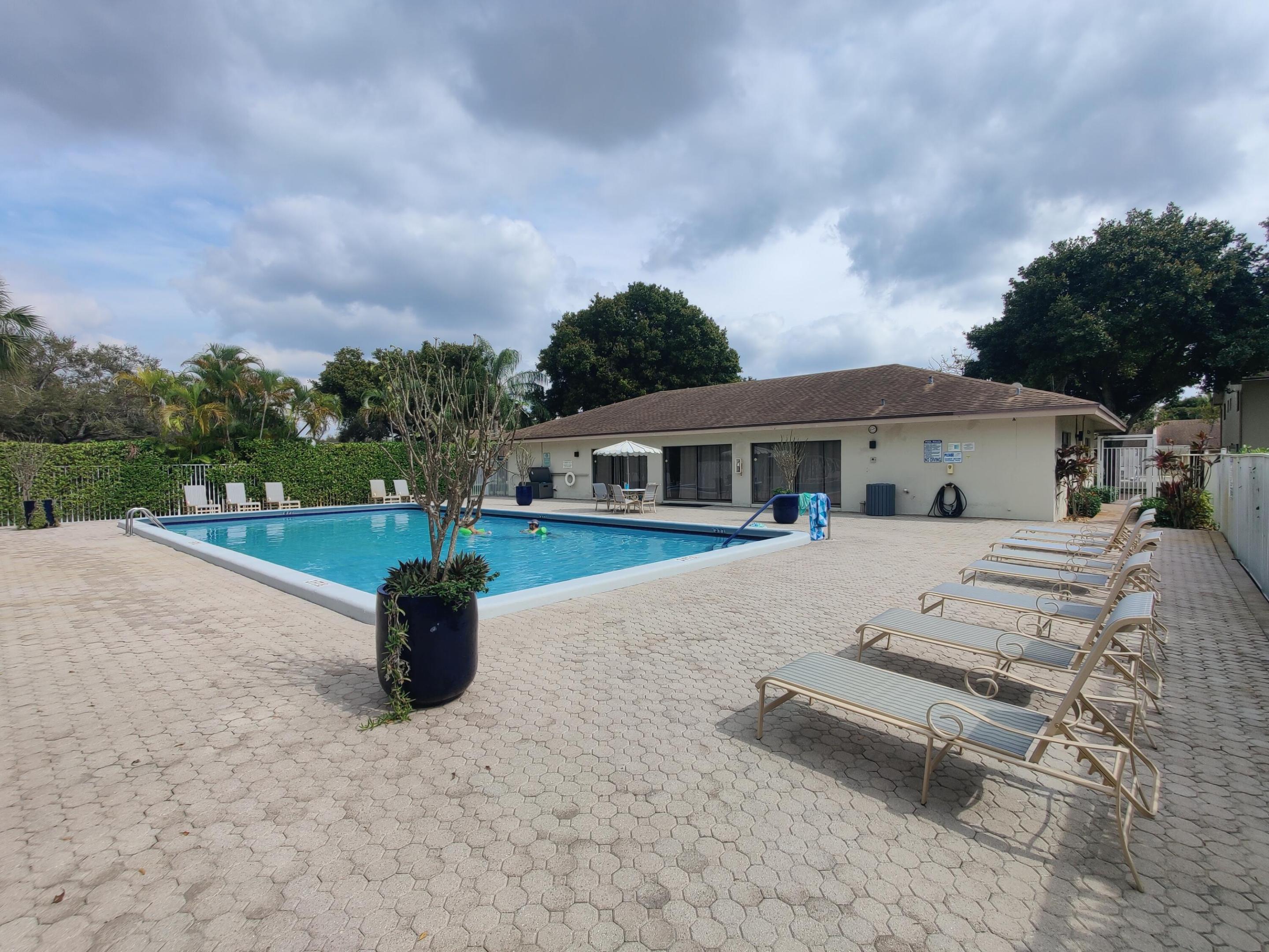 In-ground swimming pool with a concrete paver deck and perimeter privacy hedging