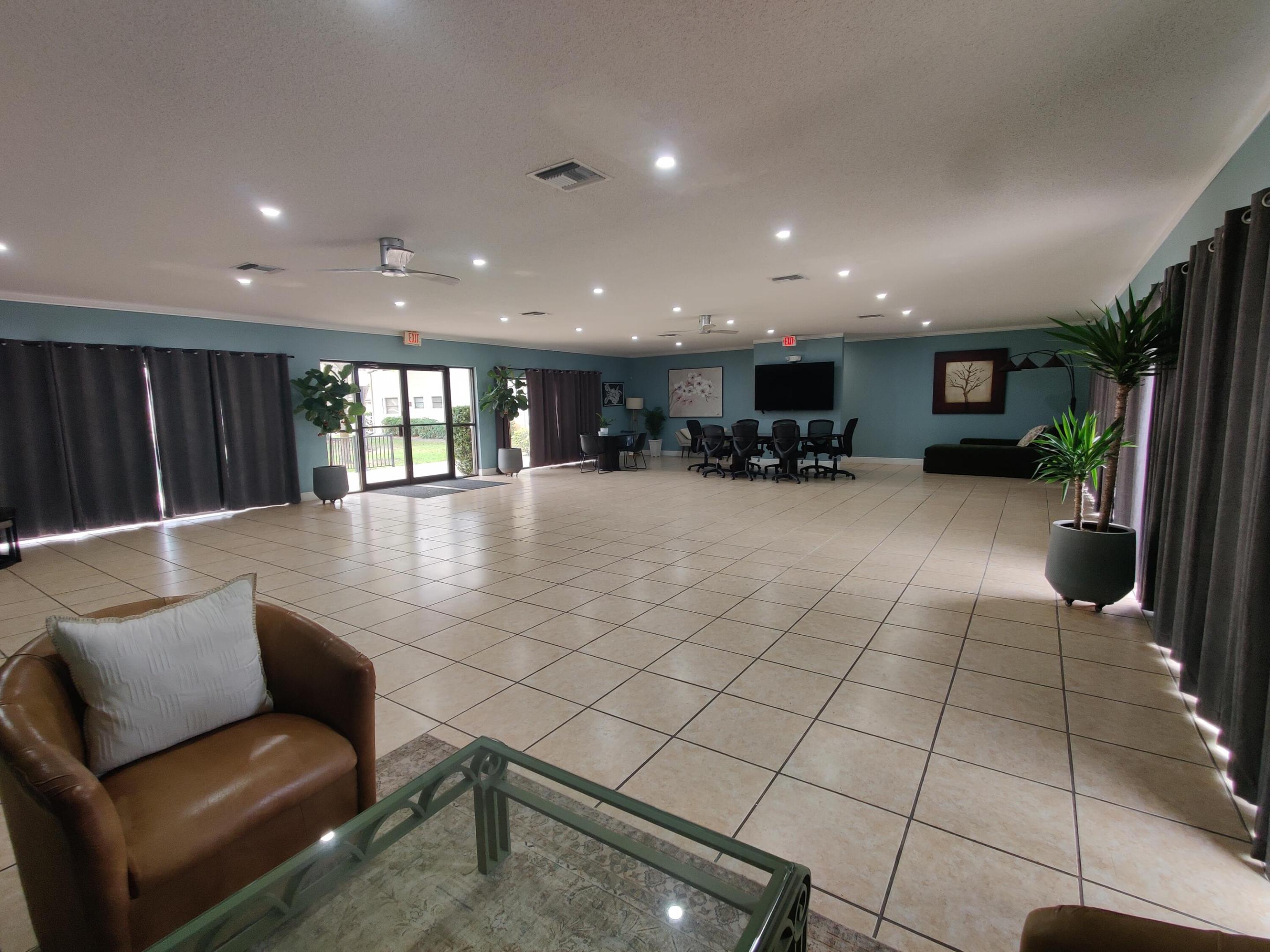 Expansive open floor plan featuring large-format ceramic tile flooring, recessed lighting, ceiling fans, and glass sliding doors