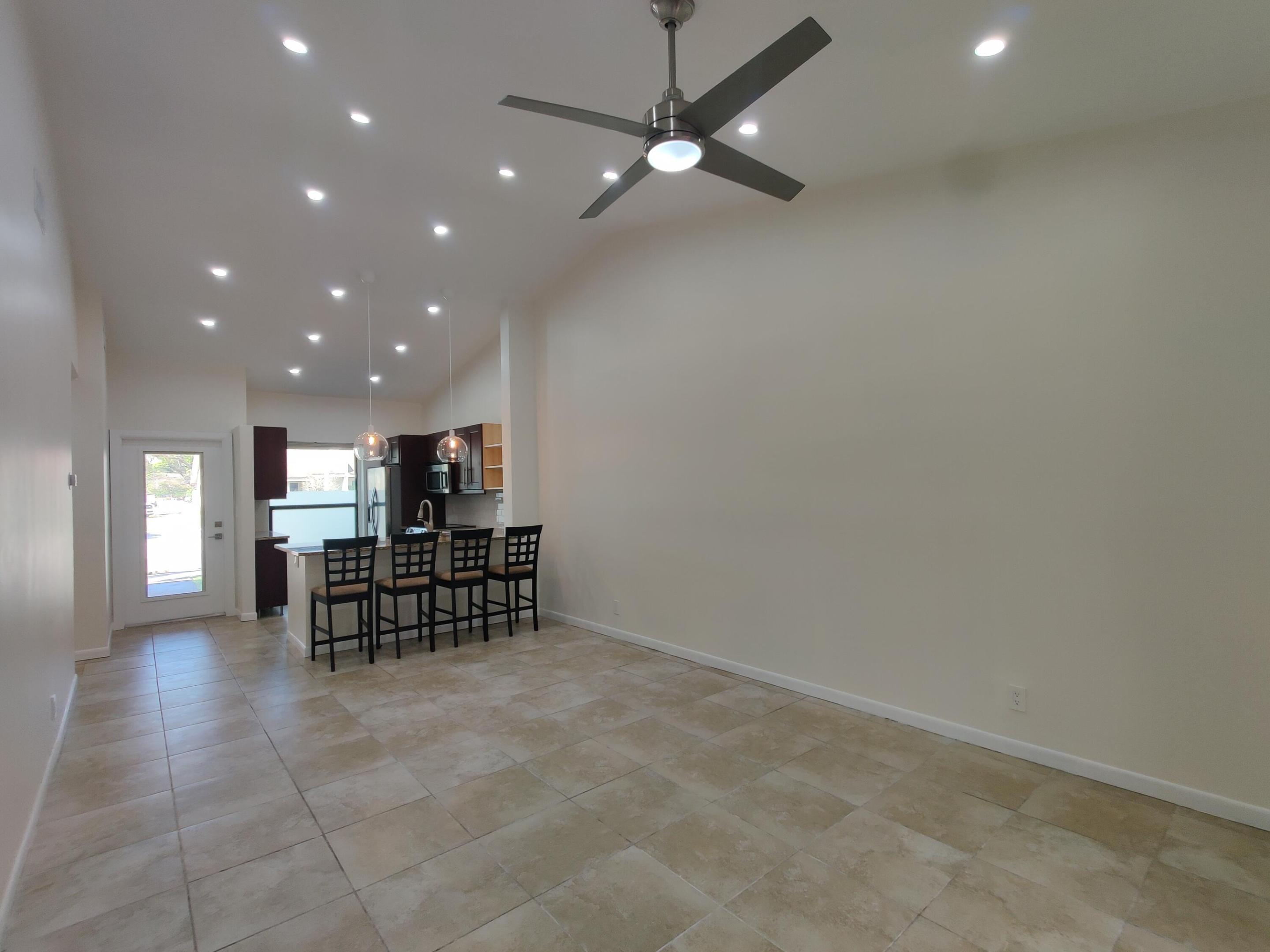 Vaulted ceilings featuring recessed lighting, a modern ceiling fan, tile flooring, and a kitchen island with dual pendant lighting