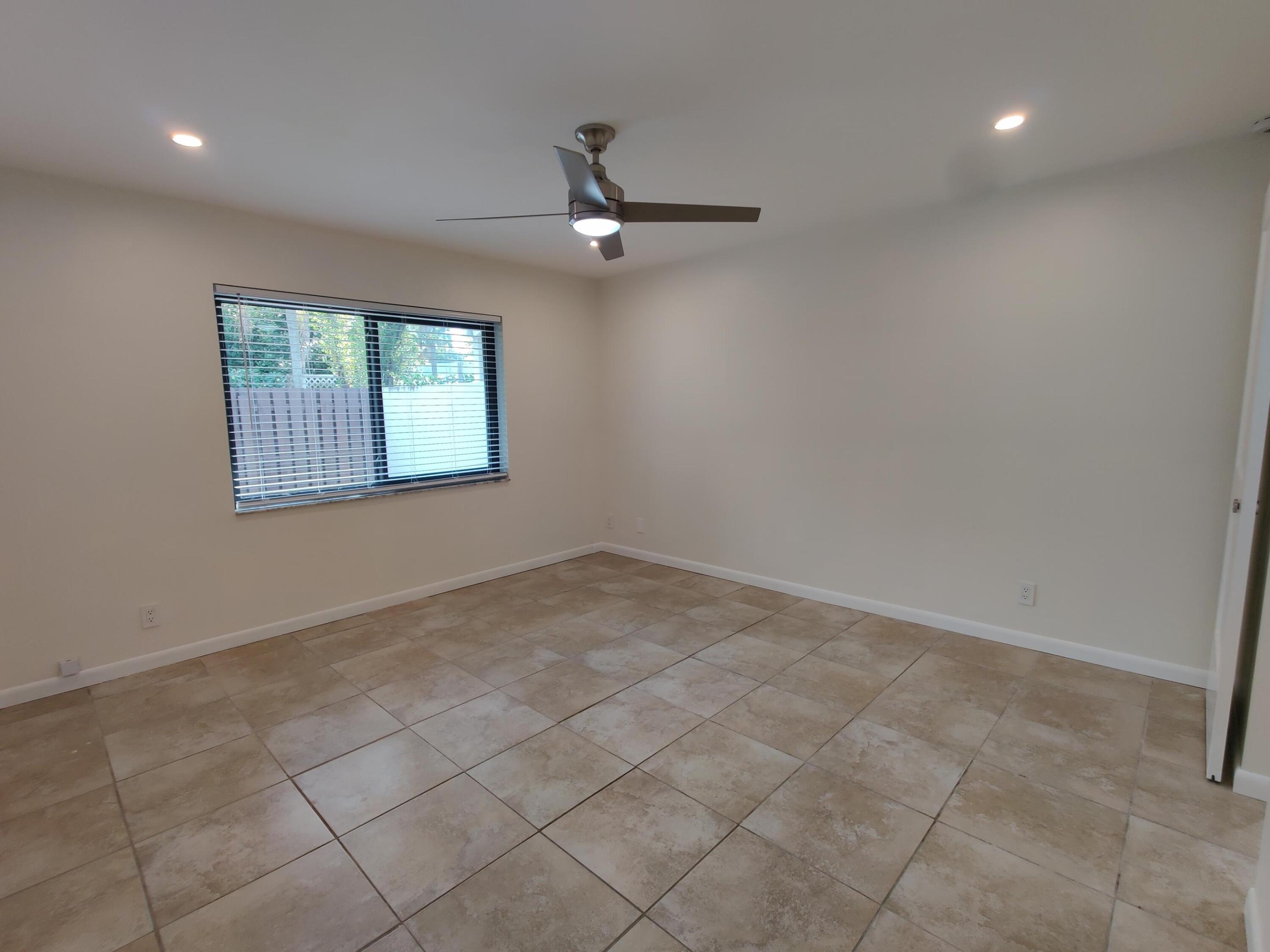 Neutral-toned room featuring large-format ceramic tile flooring, recessed lighting, and a brushed nickel ceiling fan with an integrated light fixture