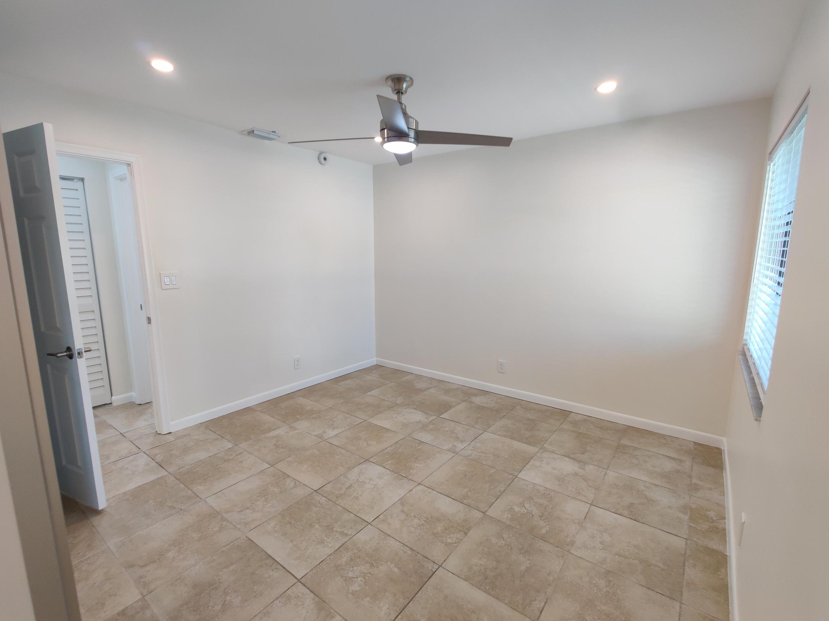 Neutral-toned tile flooring, brushed metal ceiling fan with integrated lighting, recessed ceiling lights, and louvered-style closet door
