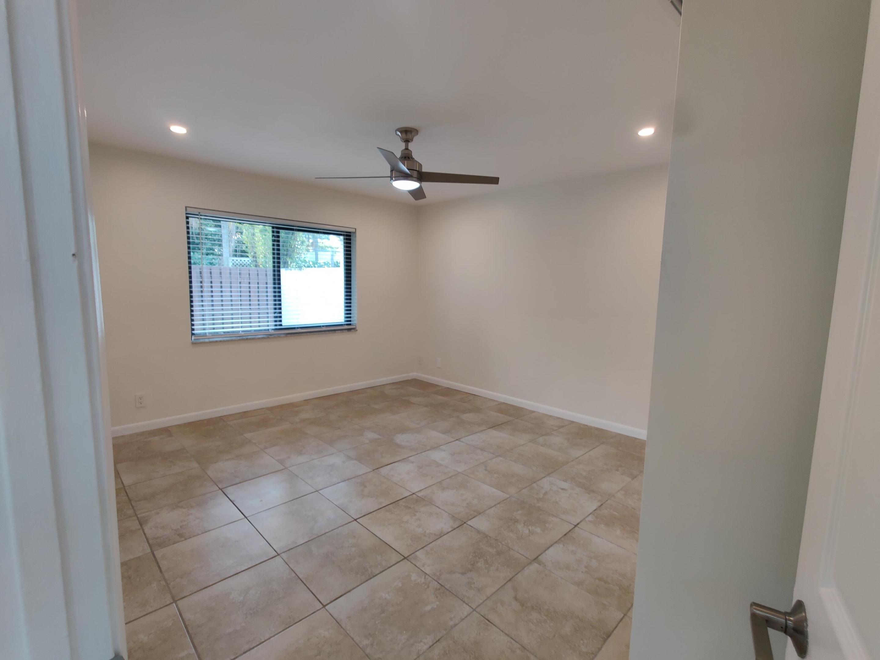 Neutral interior space featuring large-format stone-style tile flooring, recessed ceiling lighting, and a brushed-nickel ceiling fan