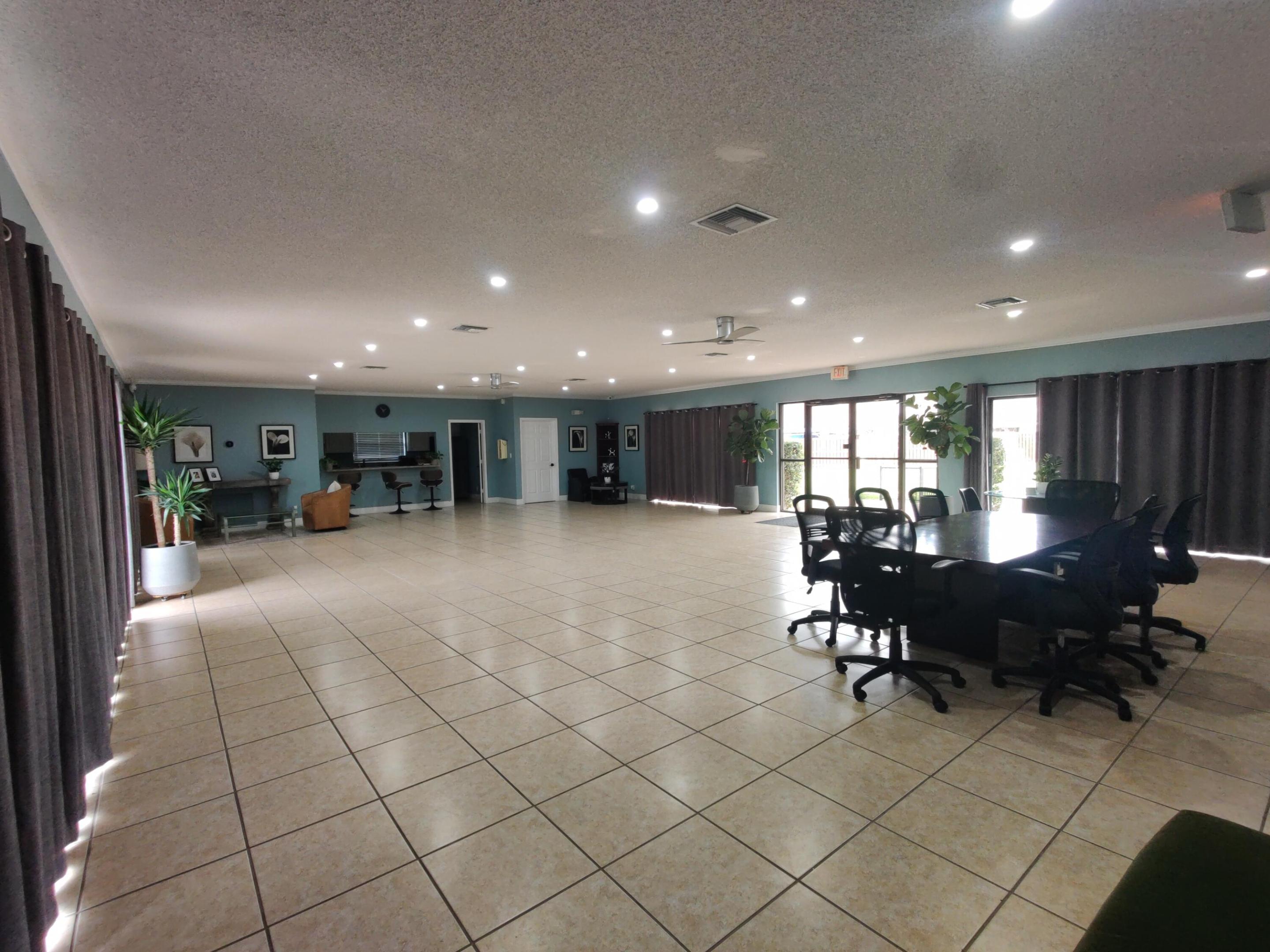 Expansive open-concept space featuring tile flooring, recessed lighting, a built-in wet bar, and multiple sets of glass exterior doors