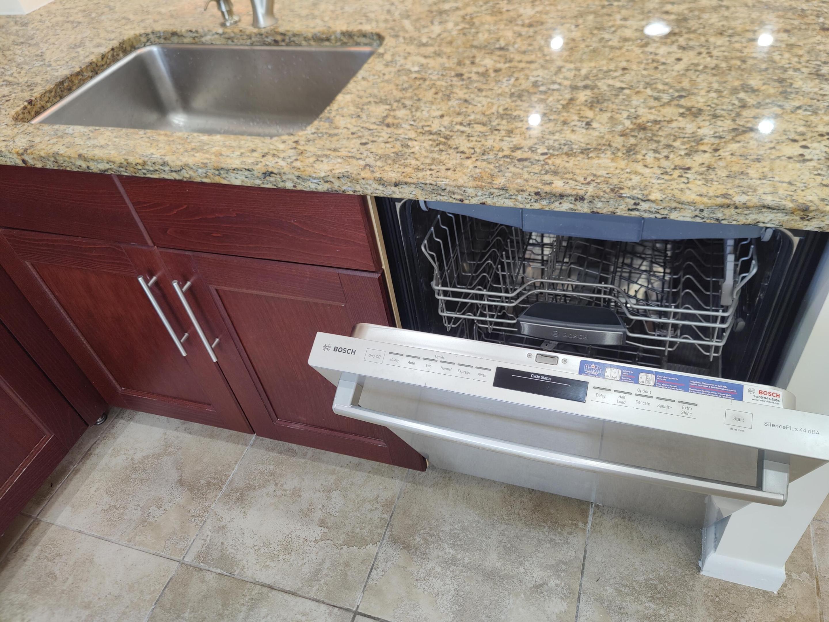Stone countertop with an integrated undermount sink, cherry-finish wood cabinetry, and stainless steel Bosch dishwasher