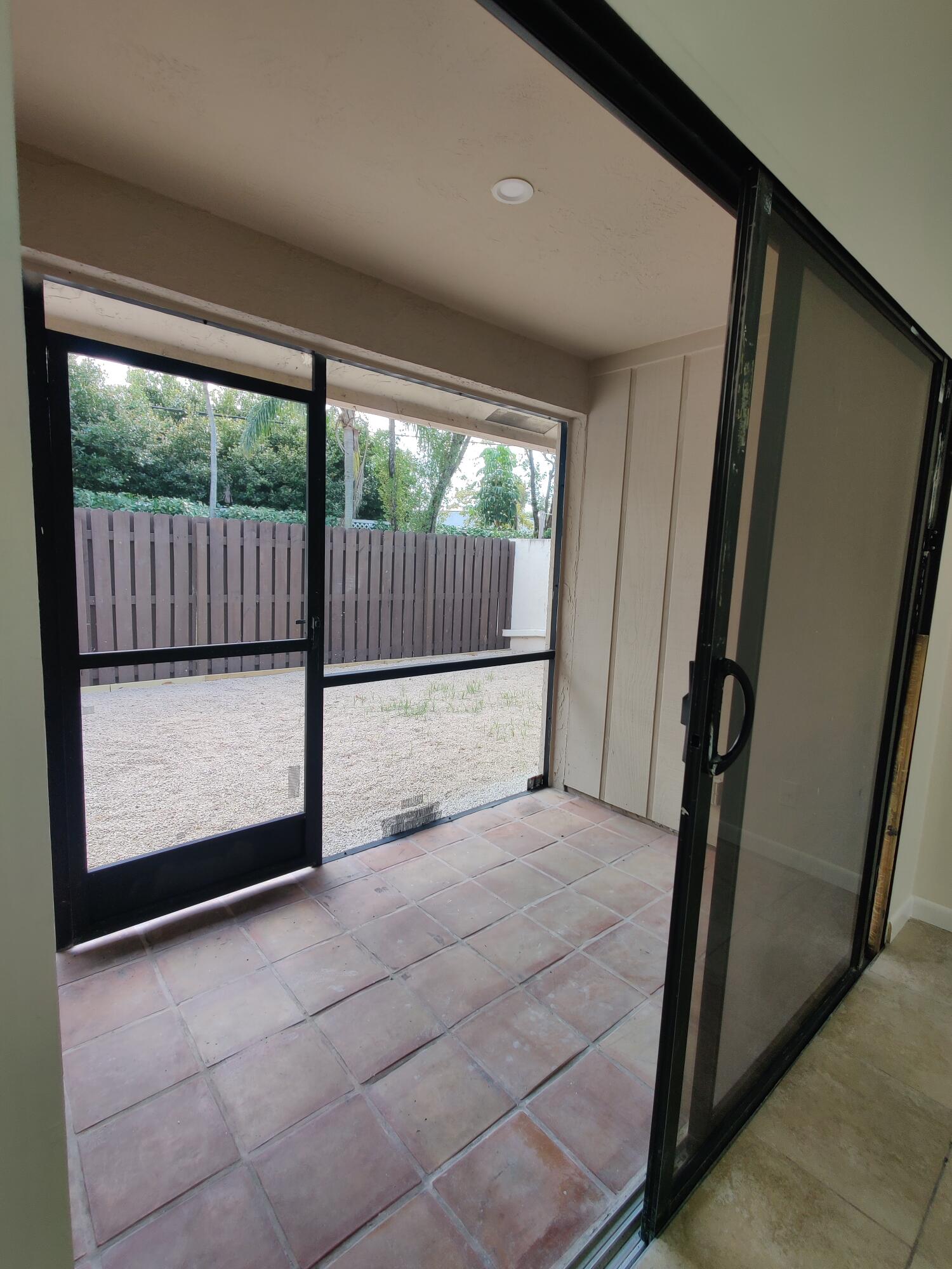 Covered patio featuring ceramic tile flooring, sliding glass door entry, and screen enclosure