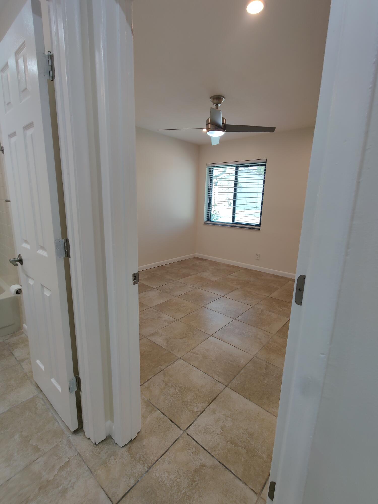 Room featuring square-tile flooring, recessed ceiling lighting, a multi-blade ceiling fan, and a single-pane window