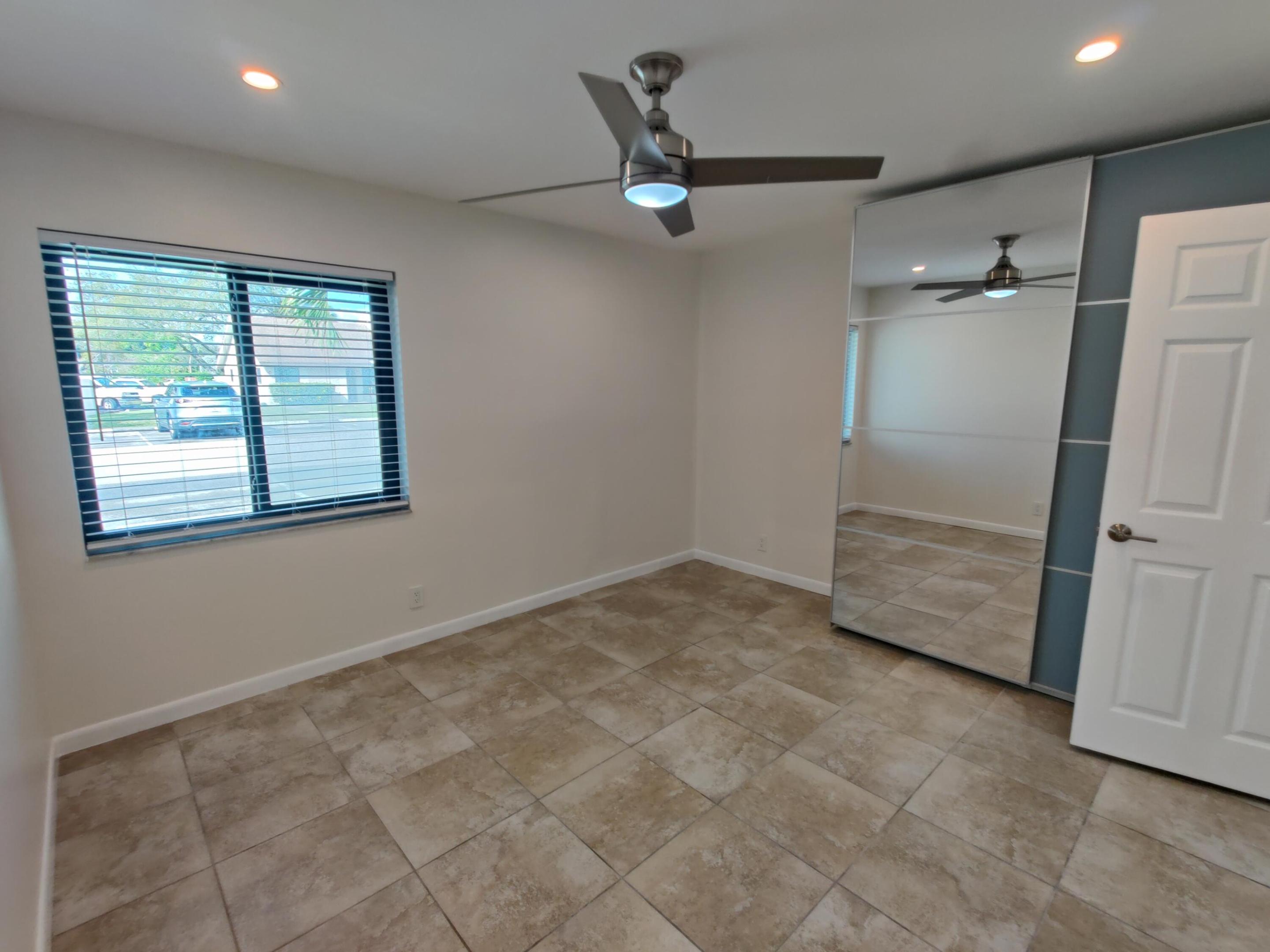 Interior room featuring tile flooring, a mirrored closet, recessed ceiling lighting, and a metal-finish ceiling fan