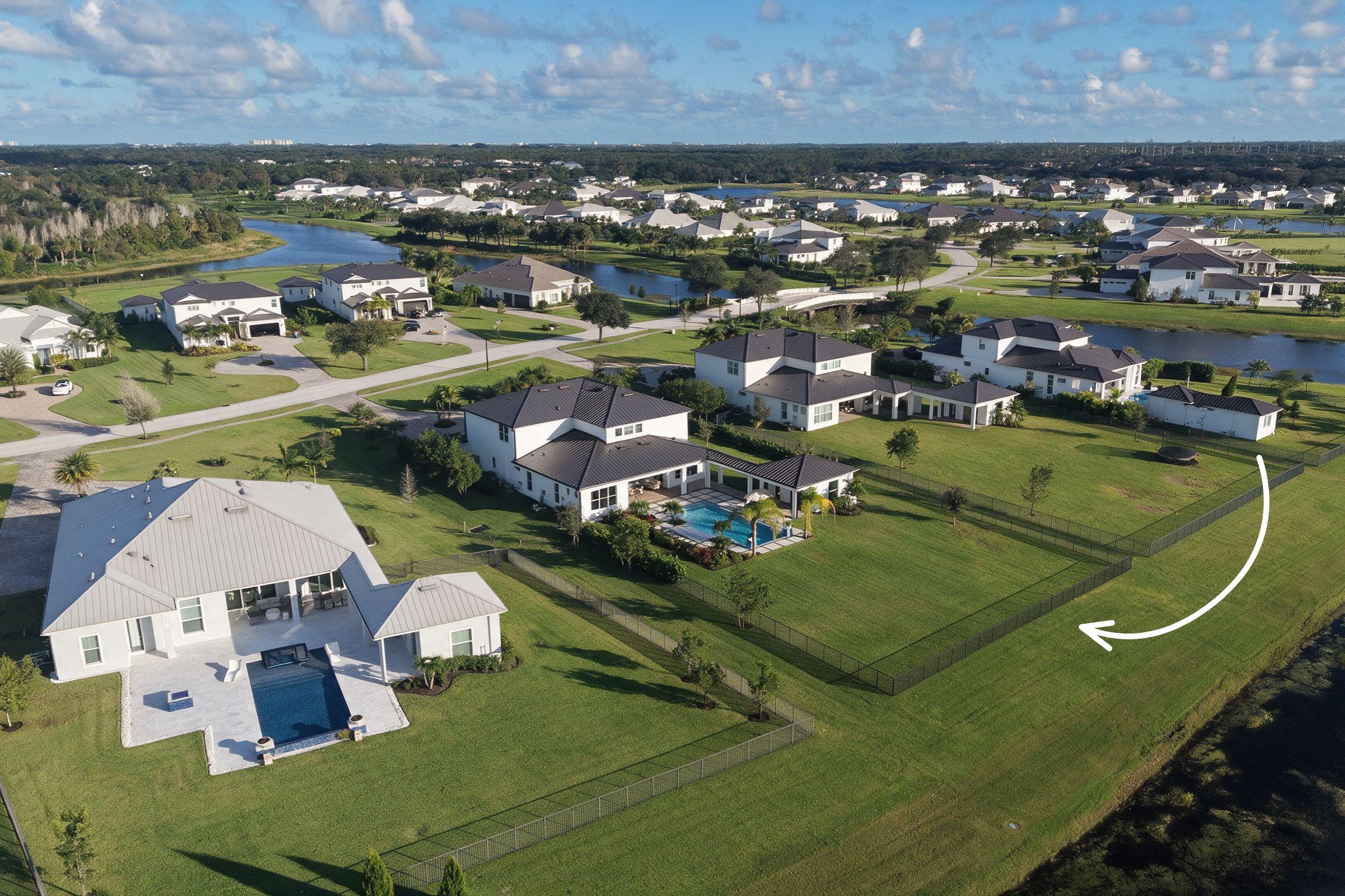 Expansive rear yard featuring manicured lawn, perimeter aluminum fencing, and structural swimming pool