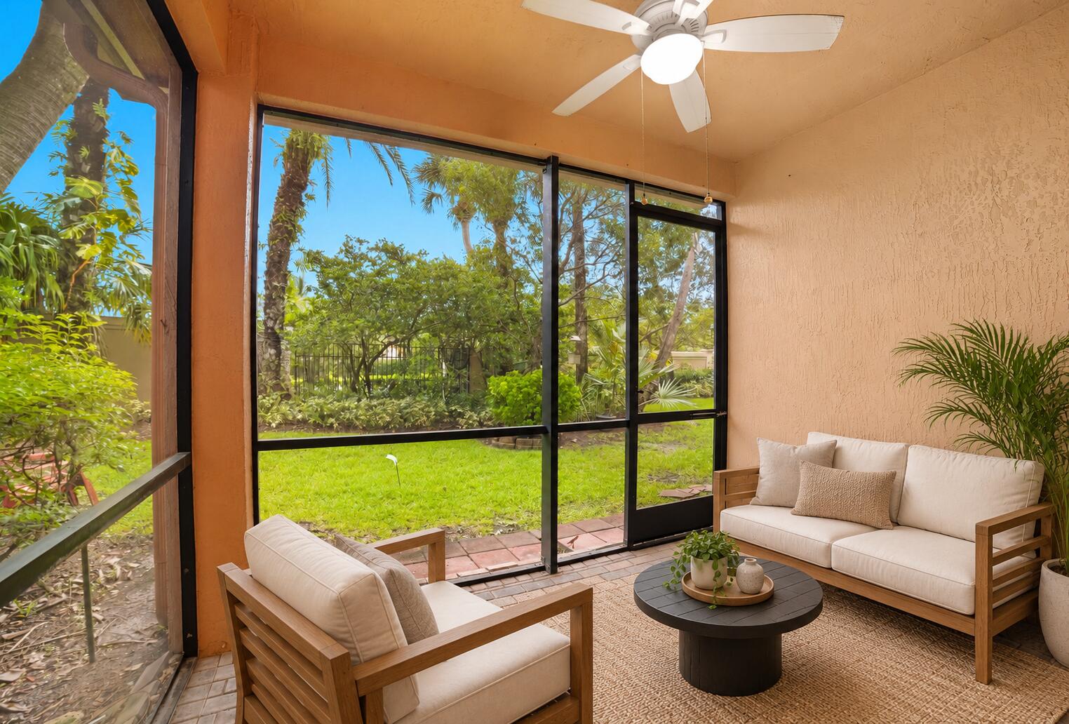 Screened-in lanai featuring a paver floor, textured walls, and a ceiling-mounted fan with integrated lighting