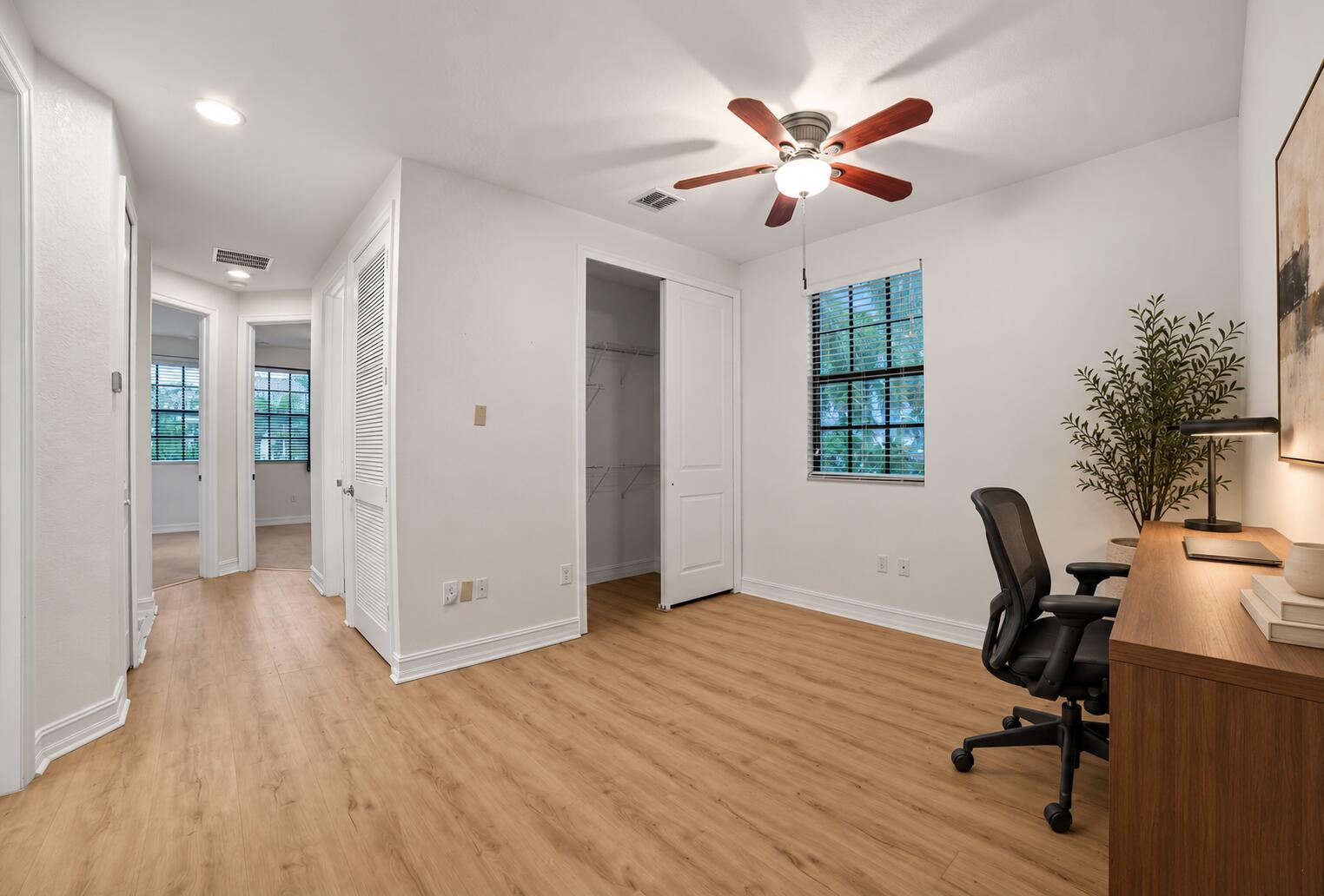 Neutral interior featuring wood-finish flooring, a ceiling fan with integrated lighting, a closet with double doors, and a window with blinds
