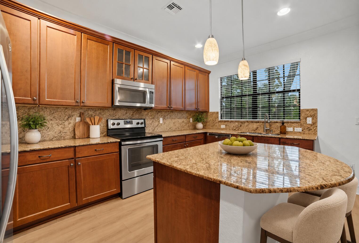 Kitchen featuring wood cabinetry, stone-surface countertops, stainless steel appliances, a central island, and dual pendant lighting
