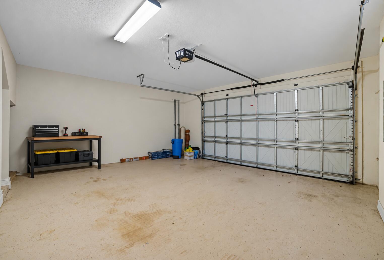 Two-car garage featuring a sectional overhead door, automated garage door opener, overhead lighting, and painted concrete flooring