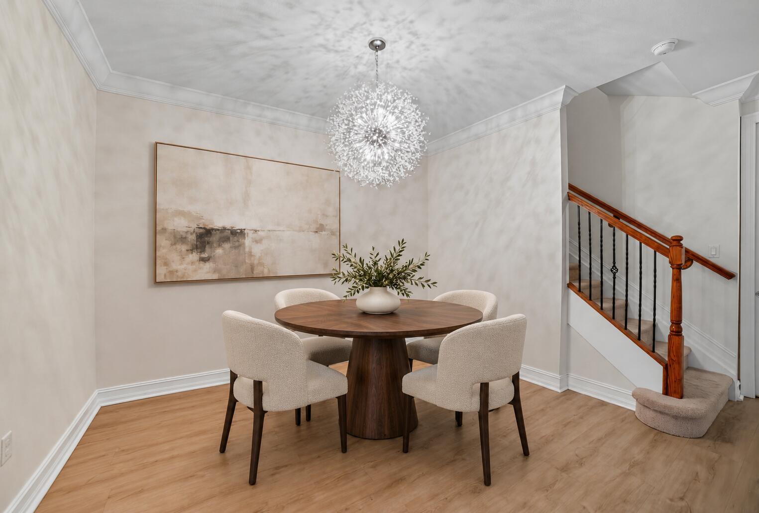 Dining area featuring wood-finish flooring, crown molding, a decorative spherical chandelier, and a staircase with a wooden handrail and black metal balusters