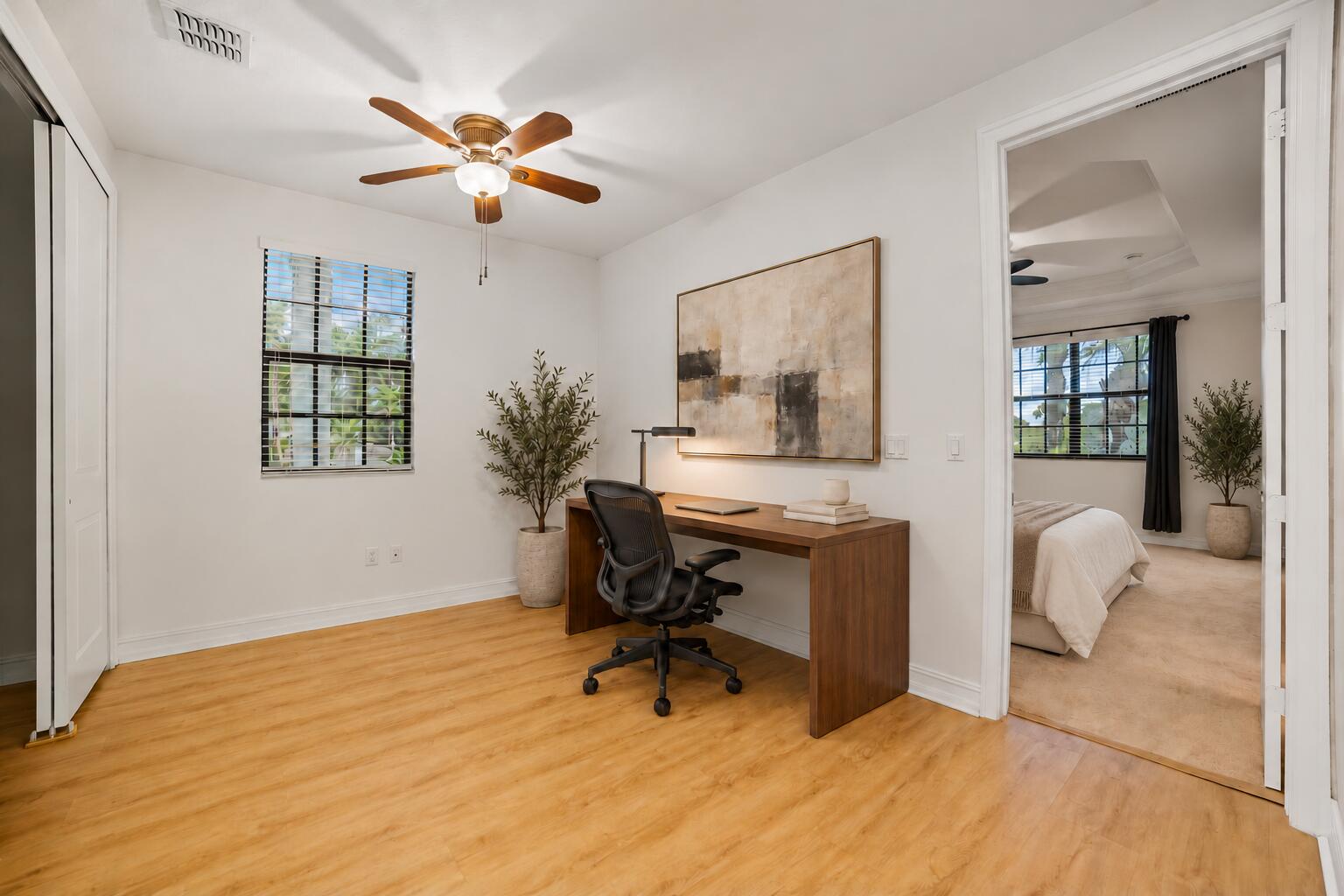 Interior room featuring wood-finish flooring, a multi-blade ceiling fan with integrated lighting, and a single-hung window with a grid pattern