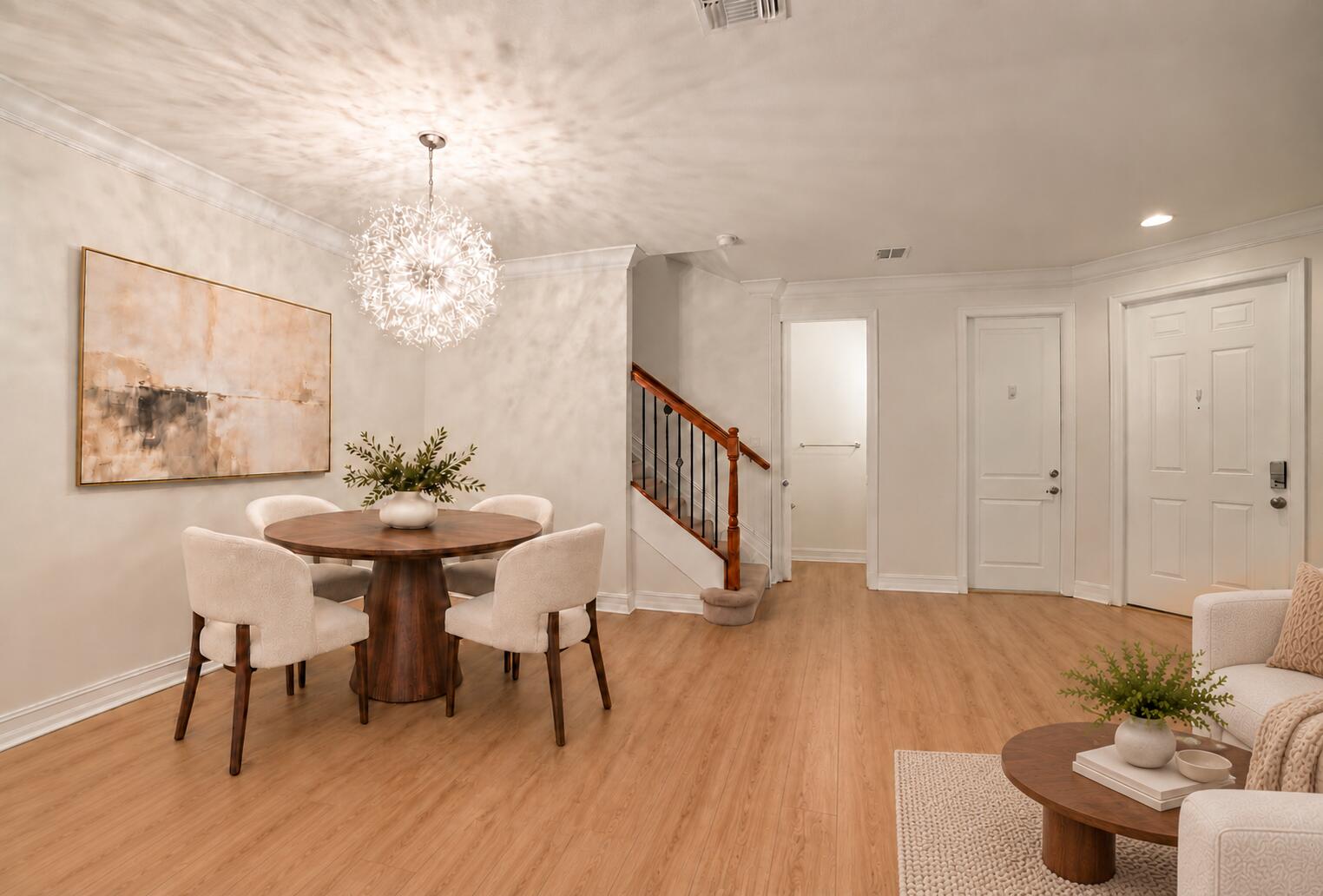 Wood-finish flooring, starburst-style chandelier, and staircase featuring a dark-toned handrail with vertical metal balusters