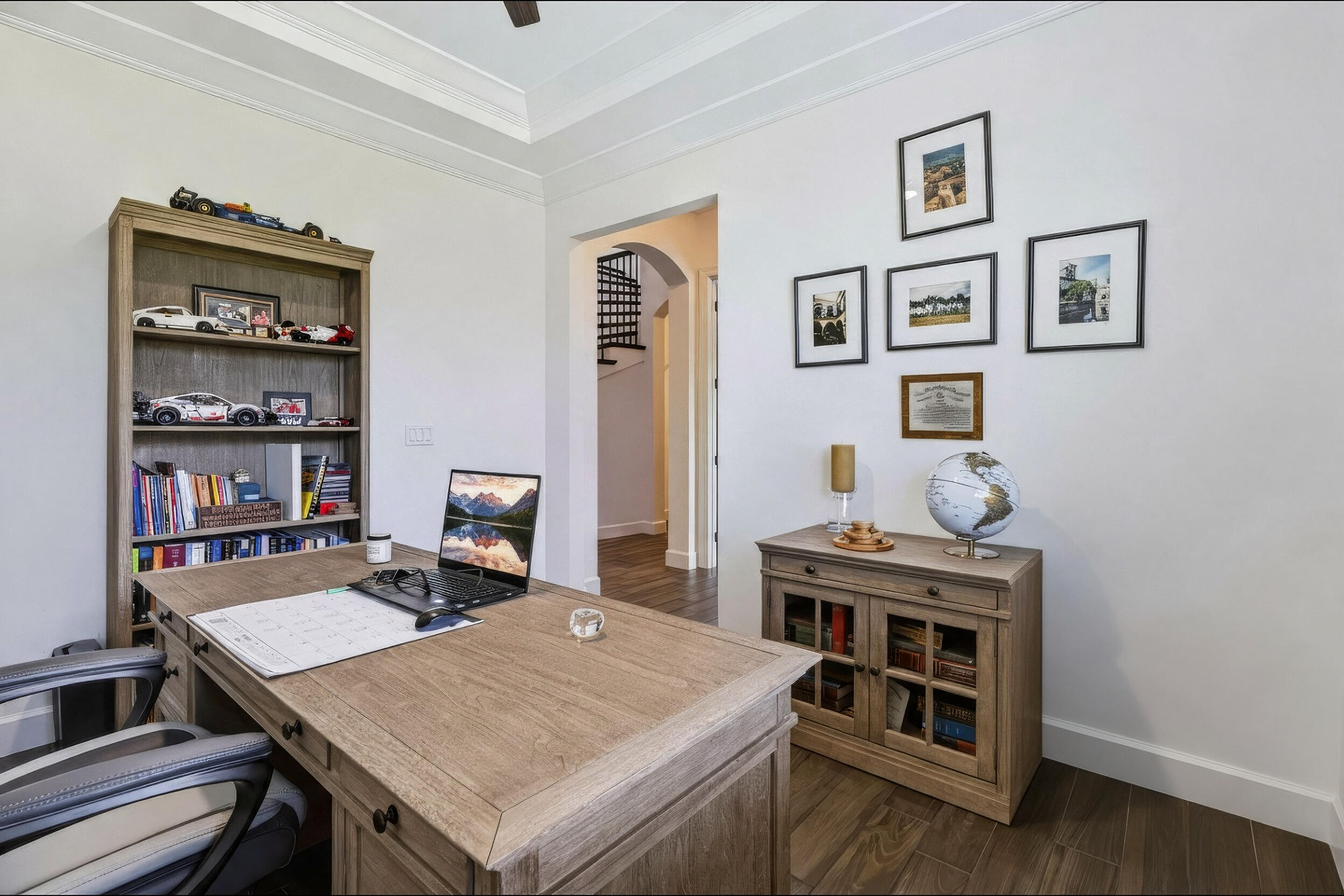 Room featuring tray ceilings, wood-finish flooring, and an arched doorway