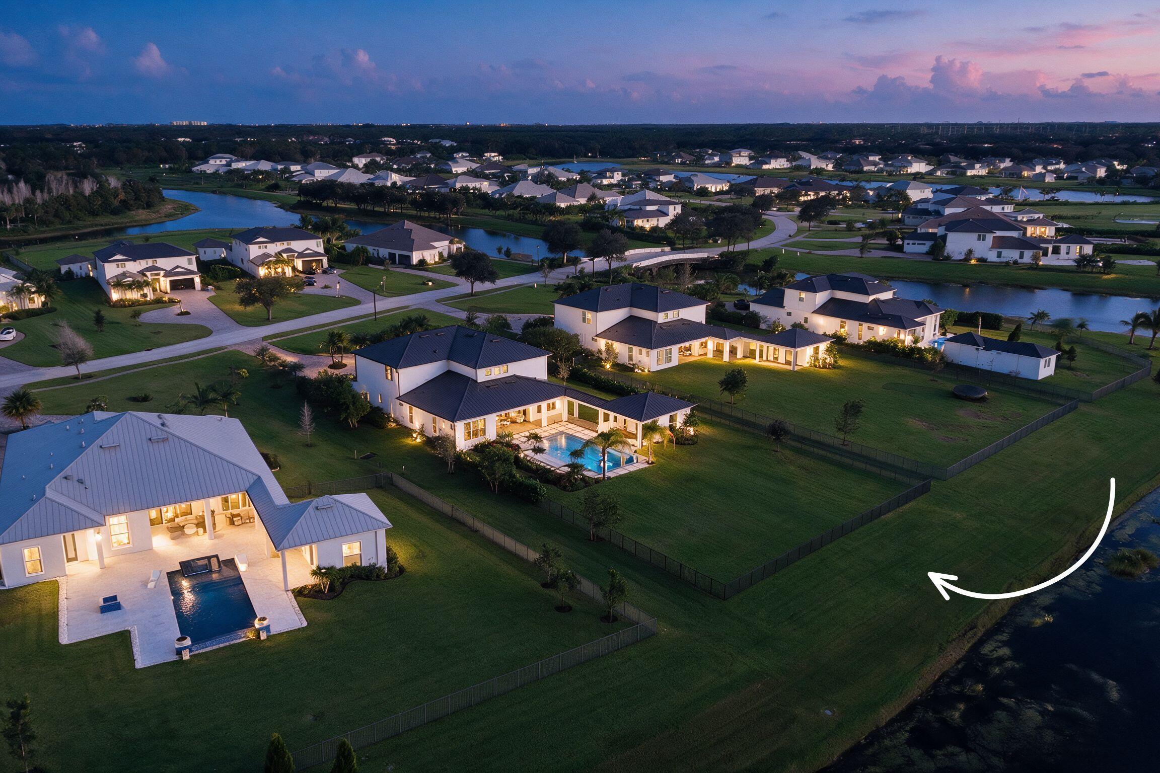 Aerial perspective of a sprawling property featuring a vast manicured lawn, an expansive rear lot boundary, and direct waterfront access