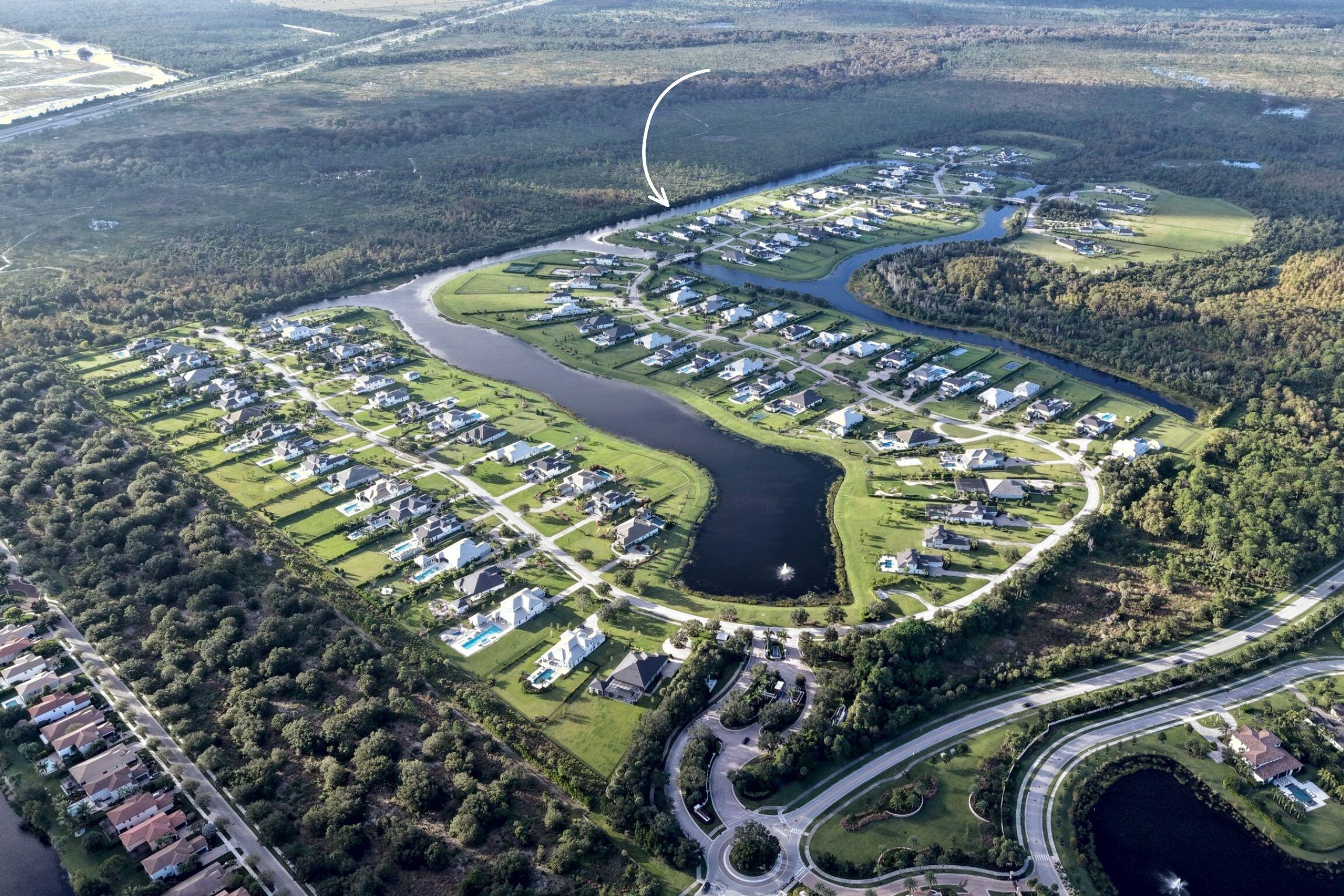 Aerial perspective of a residential development featuring expansive waterways, mature tree lines, and manicured green spaces