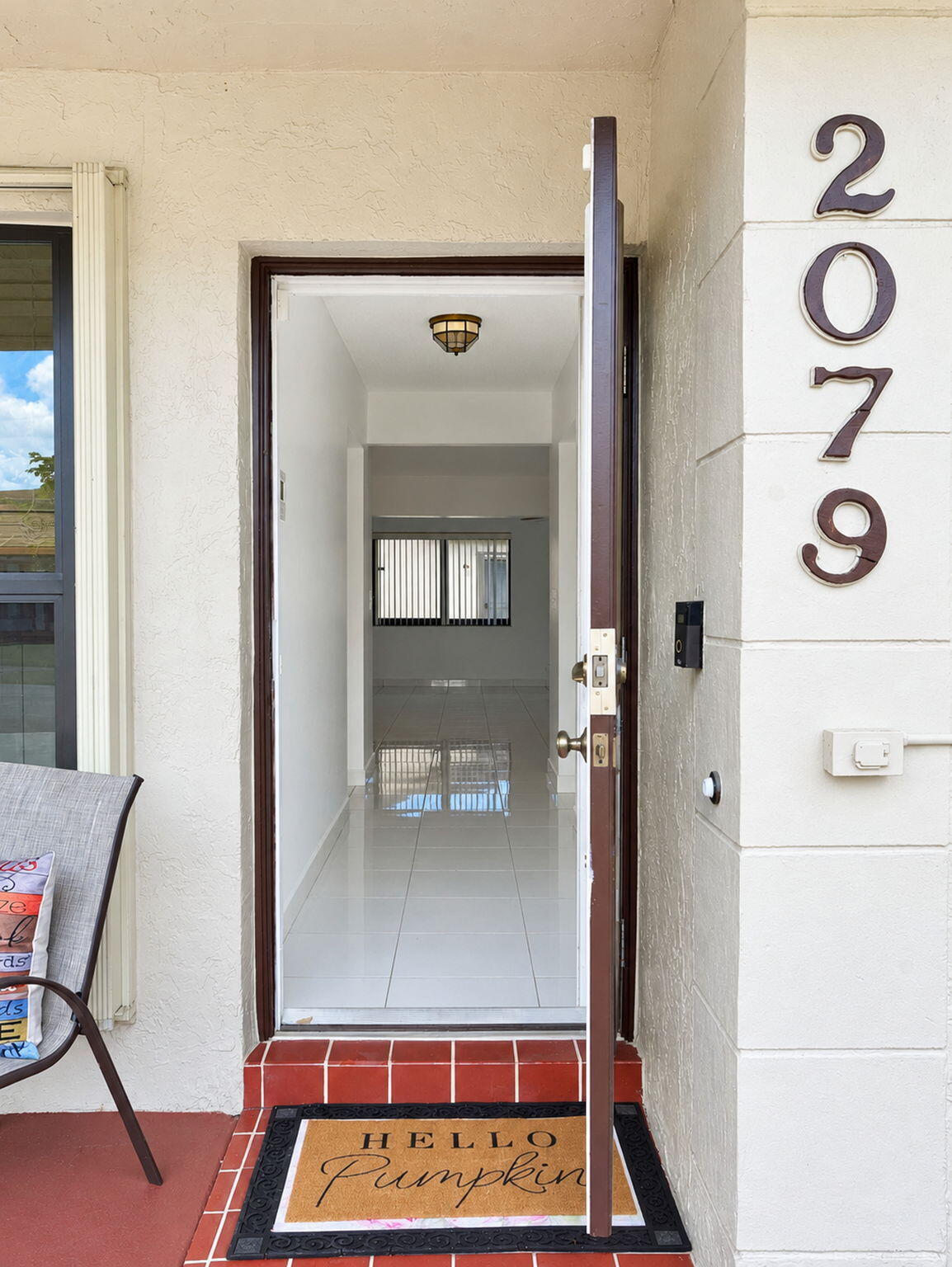 Entryway featuring a single-panel door, ceramic tile flooring, a flush-mount ceiling light fixture, and exterior address numerals