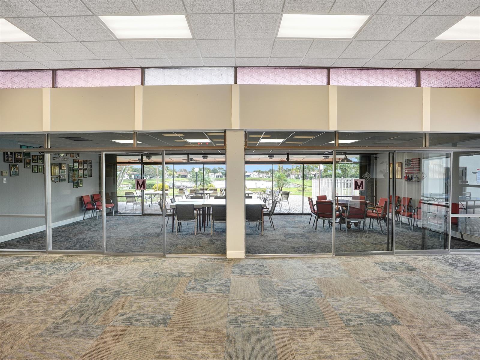 Large interior space featuring a drop ceiling with recessed lighting, full-height glass sliding wall partitions, clerestory windows, and carpeted flooring