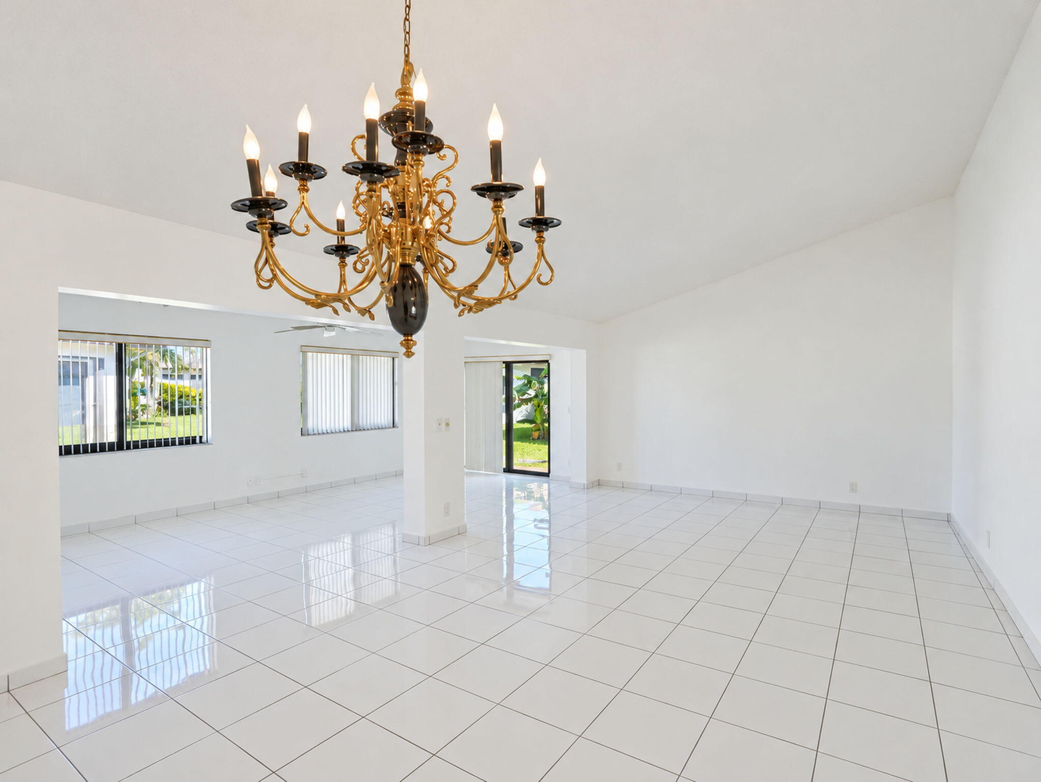 Spacious interior featuring white tile flooring, vaulted ceilings, and a decorative multi-arm chandelier
