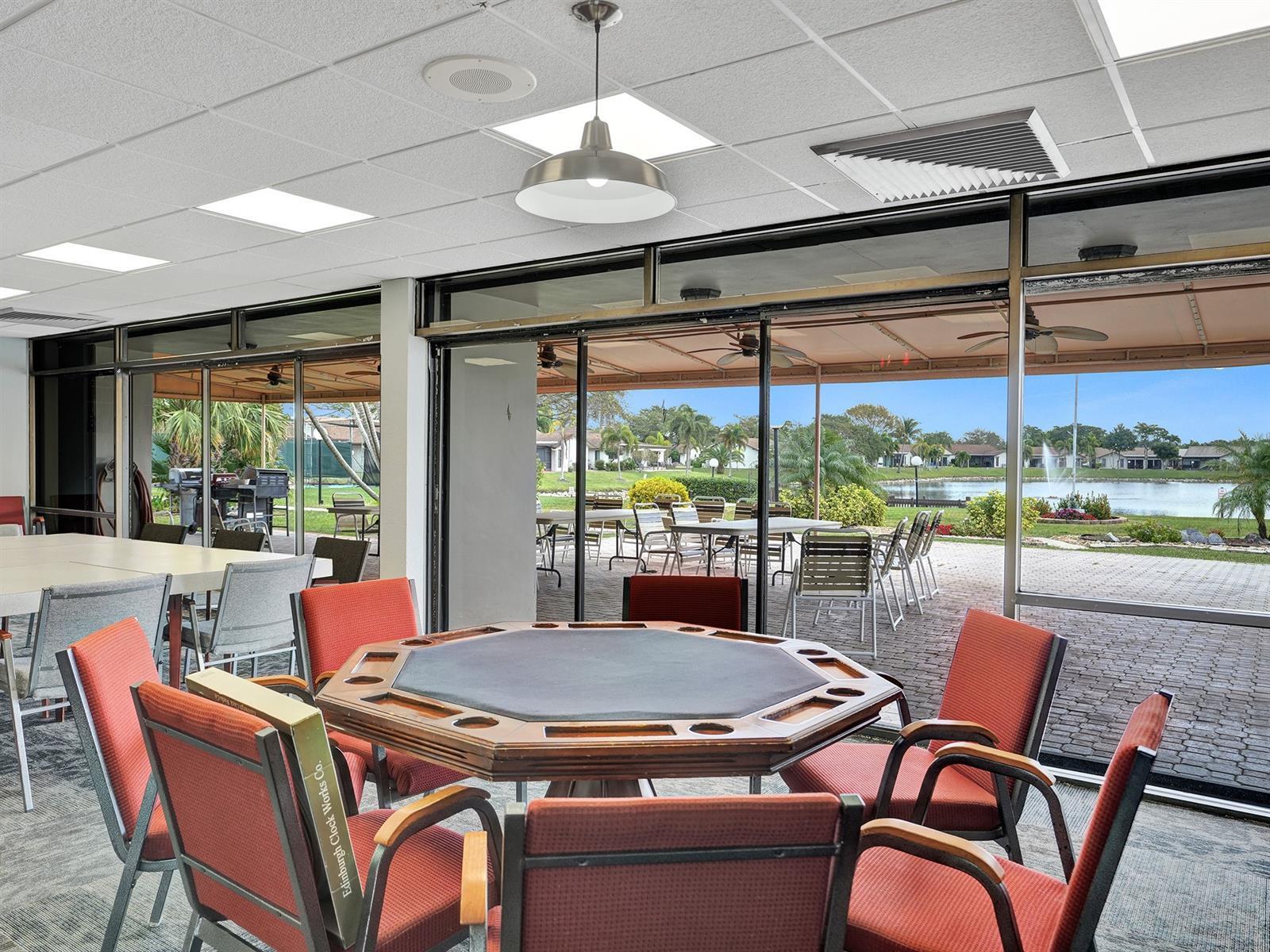 Expansive floor-to-ceiling glass wall panels with metal framing, drop ceiling with recessed lighting, pendant lighting fixture, and exterior paver patio