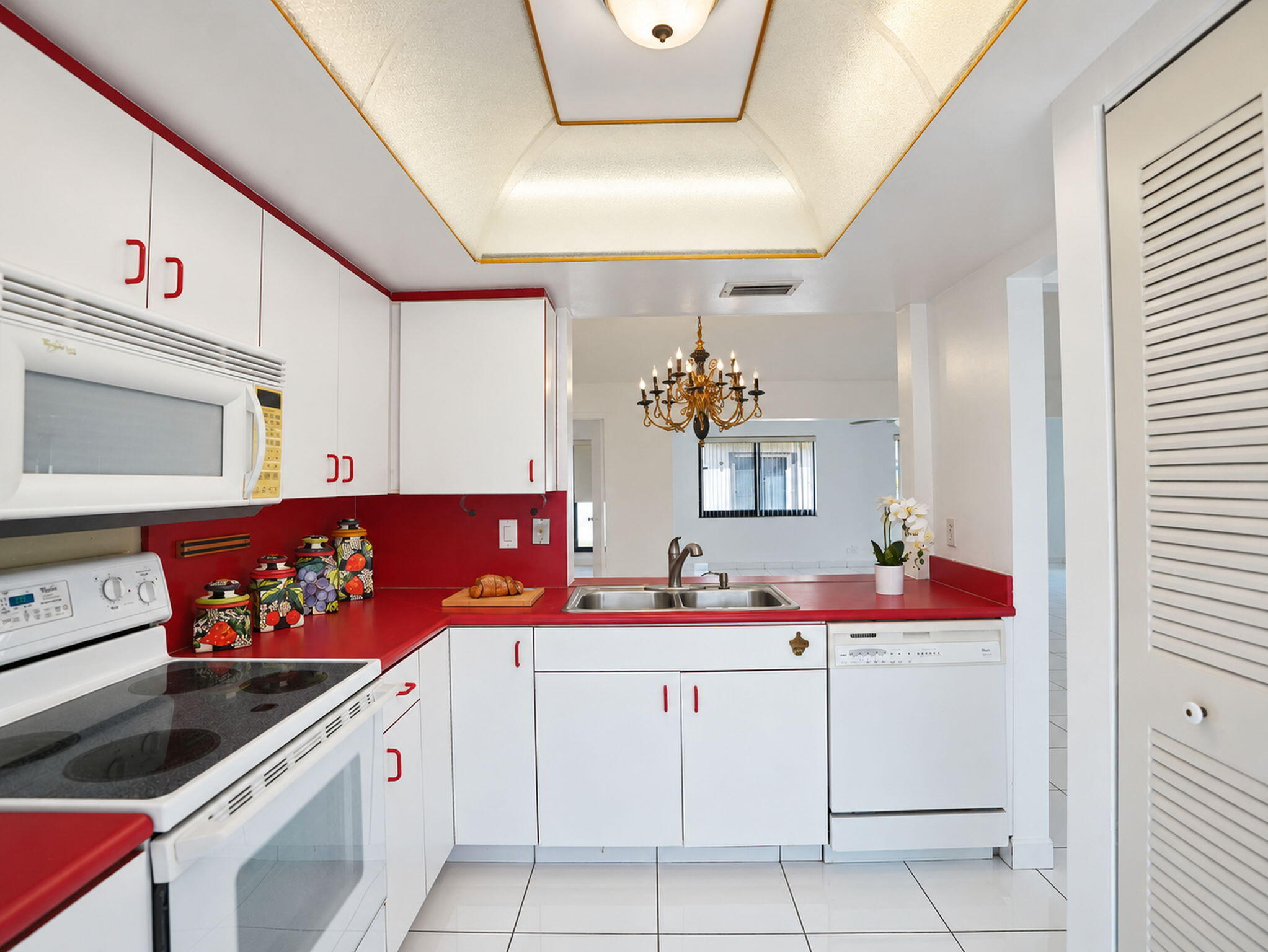 Kitchen featuring white cabinetry, contrasting solid-surface countertops, tile flooring, built-in microwave, and recessed tray ceiling lighting