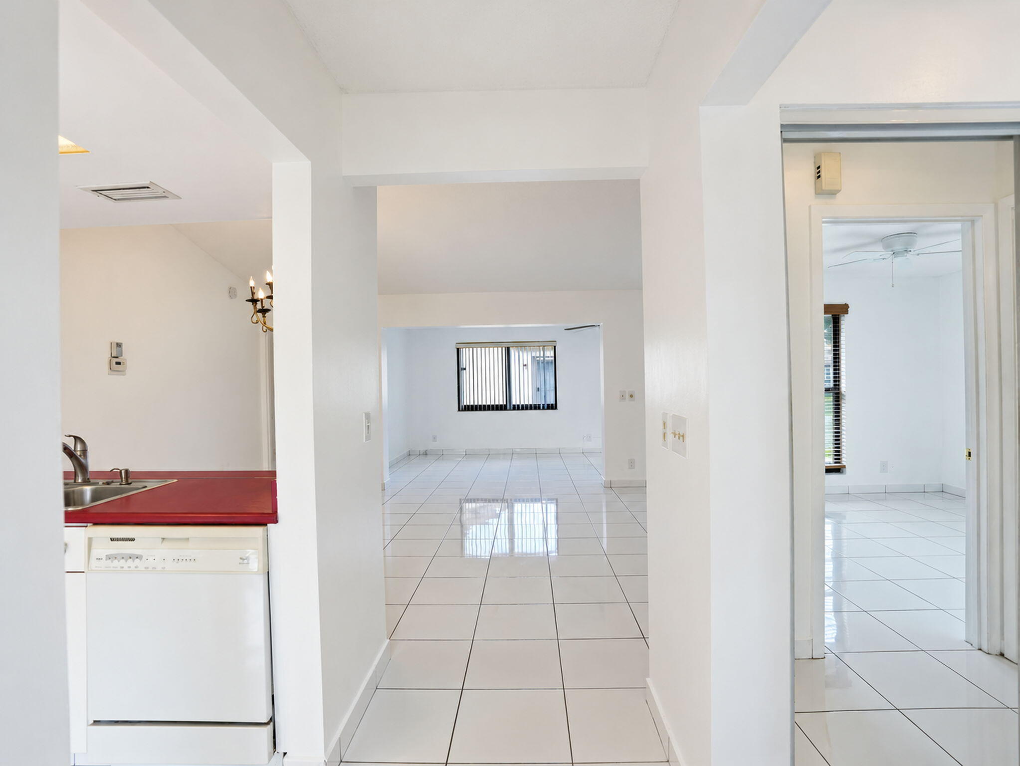 Interior featuring white ceramic floor tiling throughout, solid-surface countertops, and a built-in dishwasher