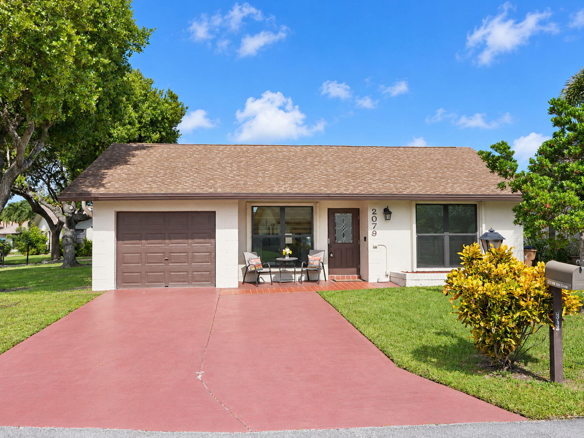 Single-story exterior featuring a shingled roof, stucco siding, an attached one-car garage, and a paved driveway