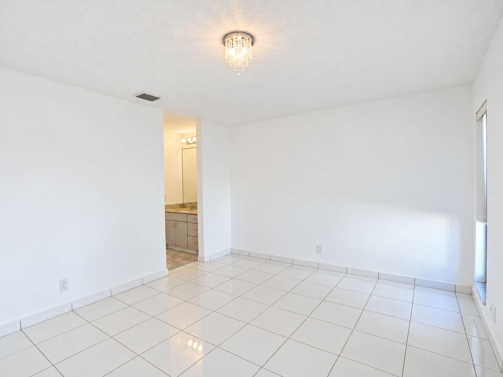 Interior space featuring white tile flooring, neutral walls, and a crystal flush-mount light fixture