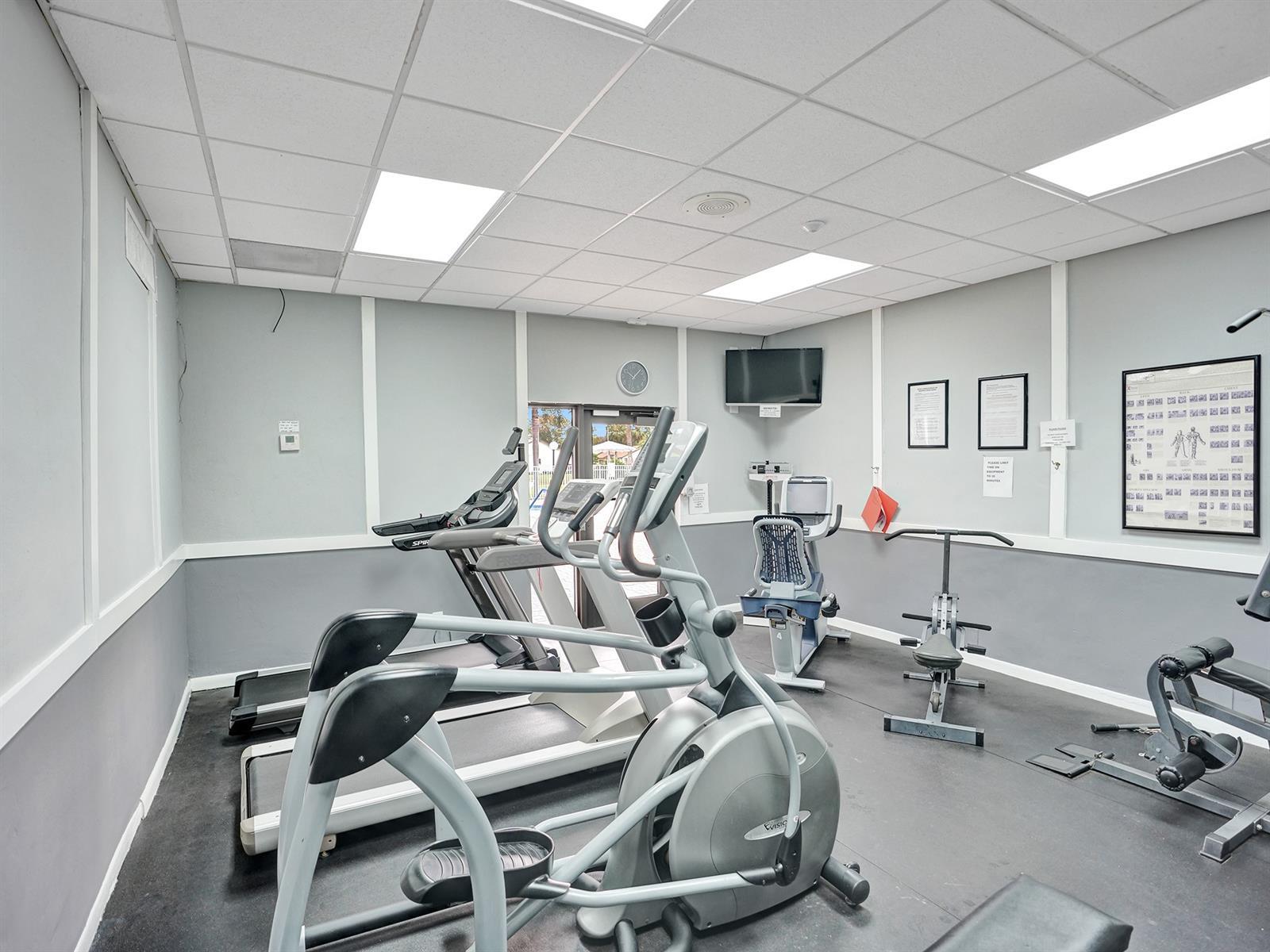 Fitness room featuring drop ceiling, recessed lighting, wall-mounted television, and resilient rubberized flooring