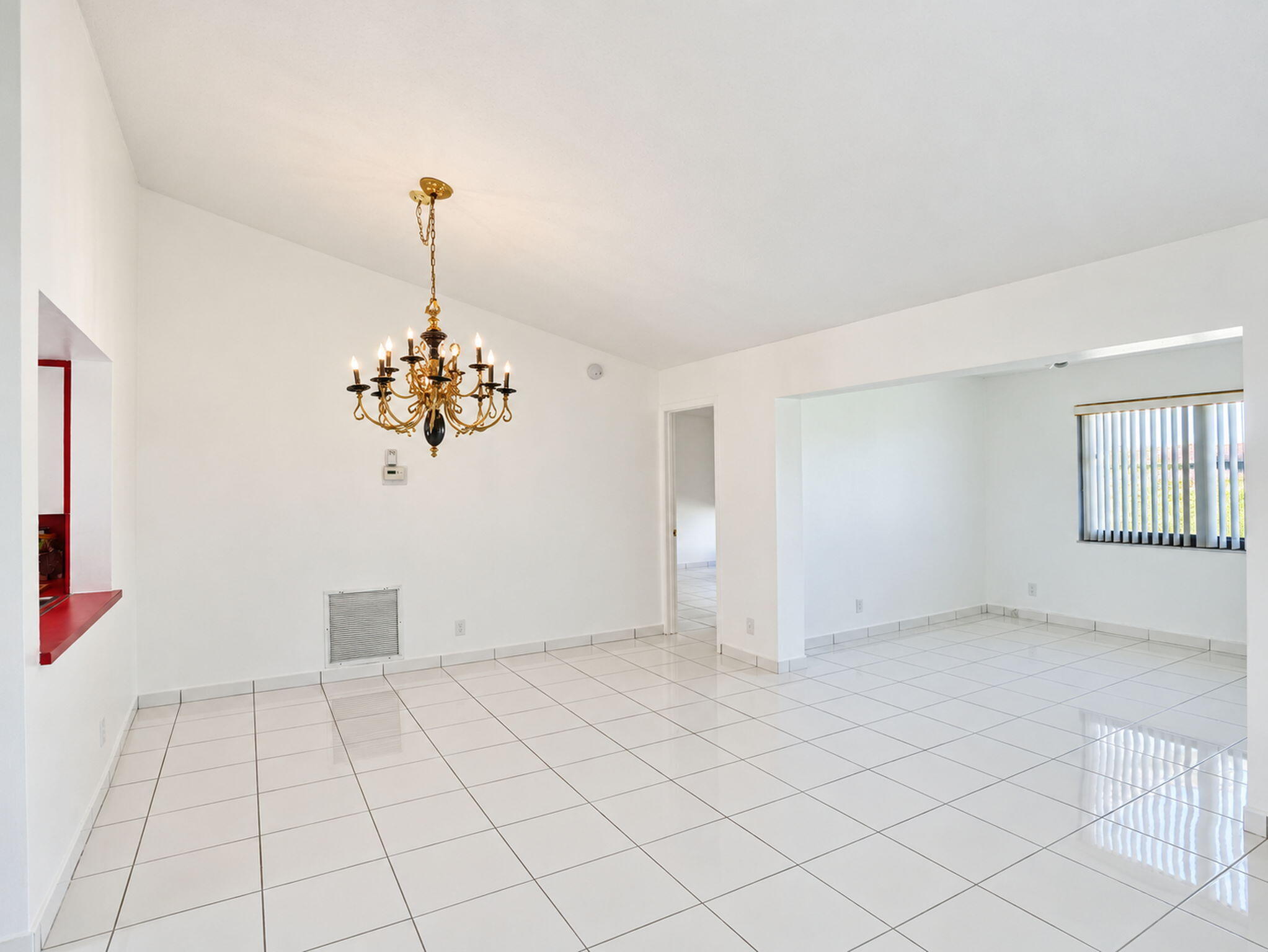 Interior featuring high vaulted ceilings, polished ceramic tile flooring, a multi-arm brass chandelier, and vertical blinds