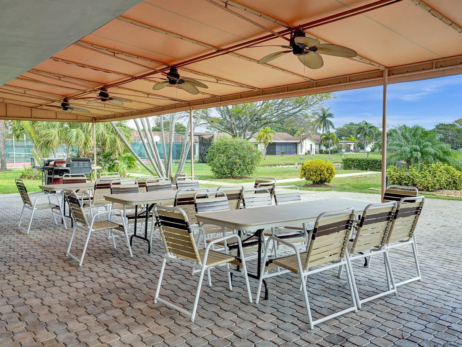 Covered outdoor patio featuring brick pavers, a structural metal canopy, and multiple overhead ceiling fans