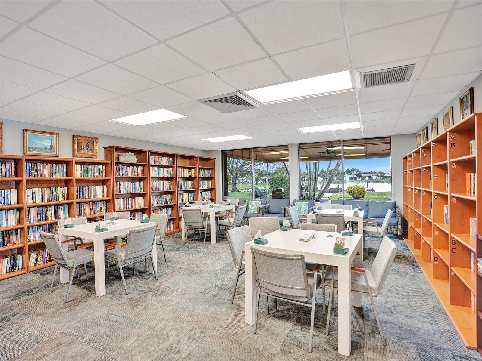 Spacious room featuring floor-to-ceiling built-in wooden shelving, patterned carpet flooring, recessed drop-ceiling lighting, and large paneled glass windows