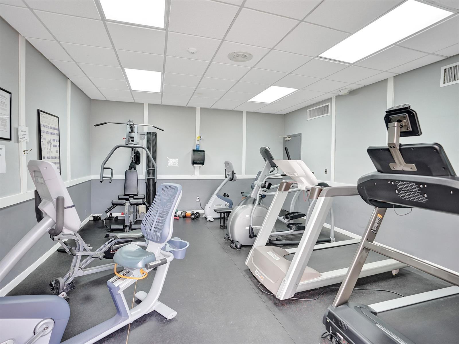 Fitness room featuring dual-tone wall paneling, durable rubber flooring, and recessed ceiling lighting